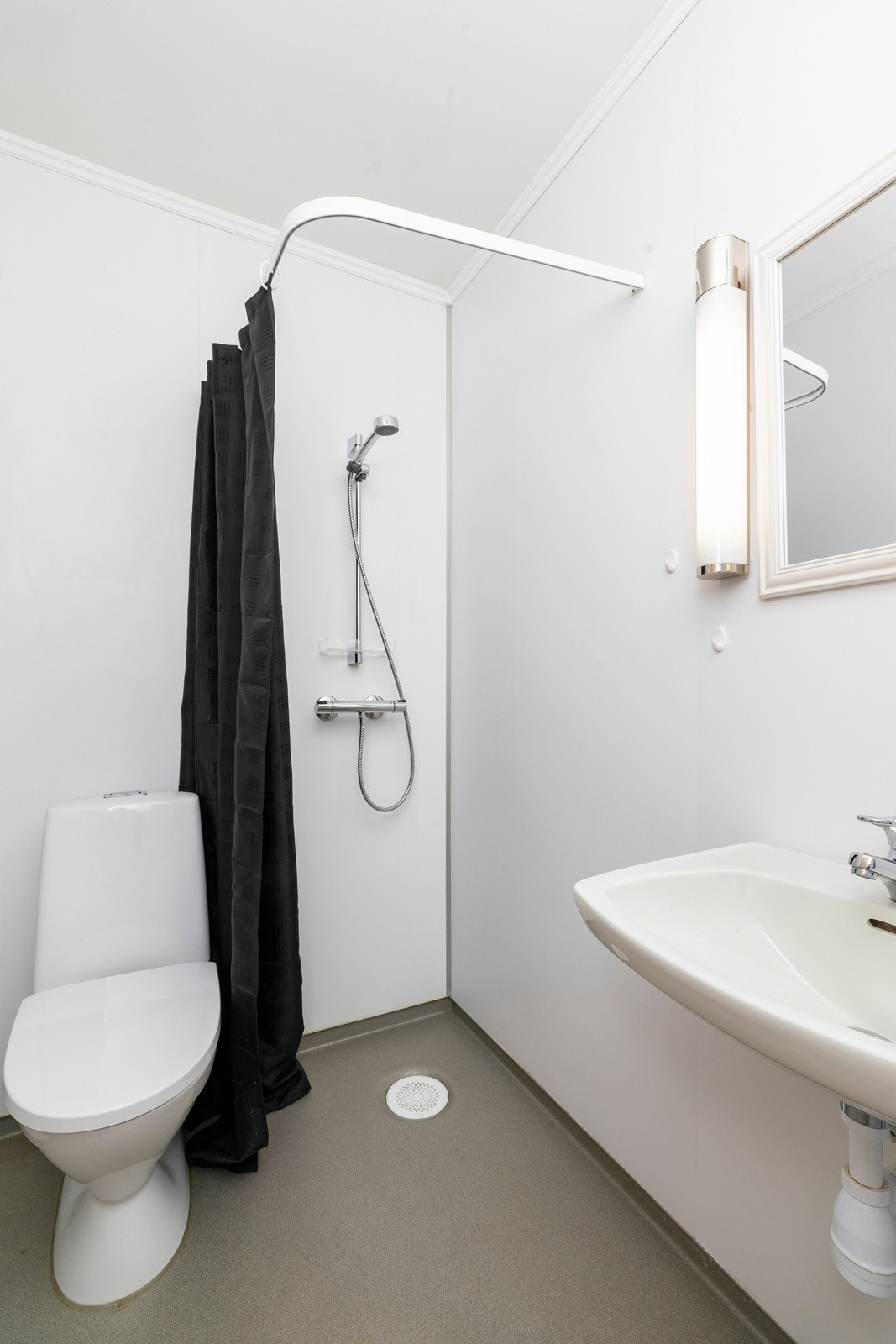 Bad nr 2 i leilighet 1 er enkelt innredet med servant, wc og dusj med forheng Galleribilde