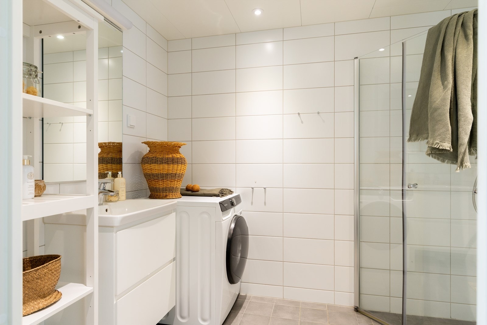 Badet har sanitærutstyr som består av veggmontert toalett, dusjhjørne vegg og dør i herdet glass og baderomsmøblement med servant, skuffer, speil og belysning. Galleribilde