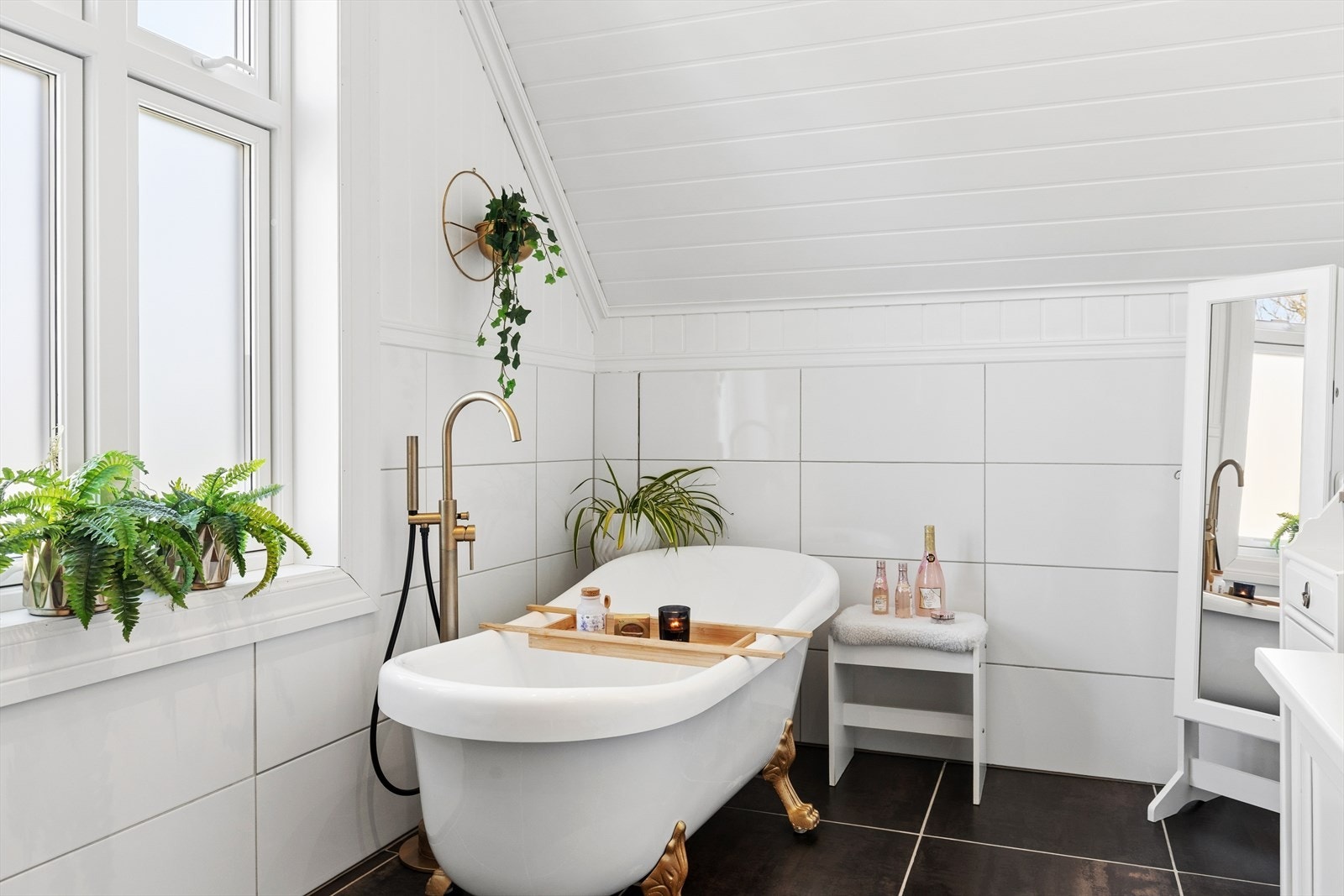 Badet er flislagt med varmekabler i gulv og med plass til både et frittstående badekar og en dusjnisje med vegger i glassbyggerstein. Galleribilde