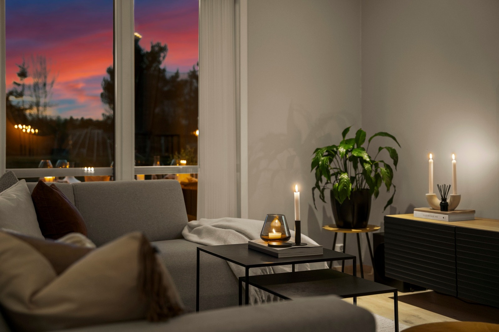 De store vindusflatene slipper inn kveldslyset og gir stuen en lun stemning, hvor levende lys, peisvarme og utsyn mot terrassen skaper en ekstra hyggelig ramme rundt hjemmet. Galleribilde