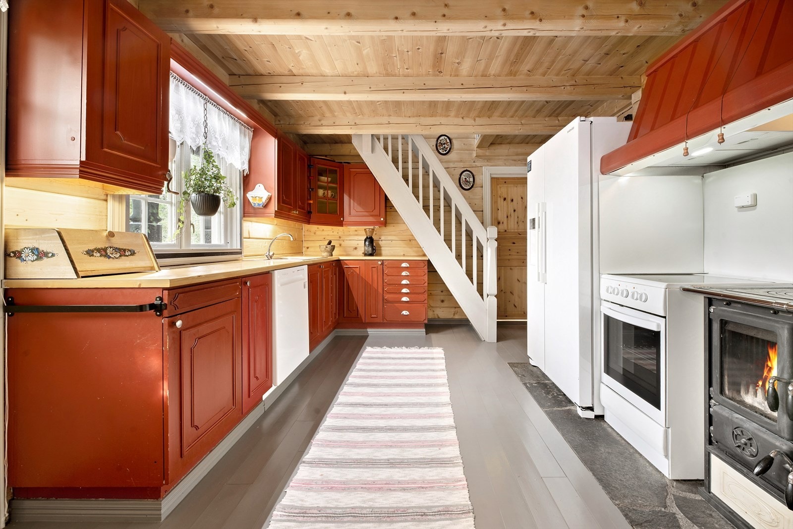 Fra gangen kommer man videre inn til kjøkkenet. Et kjøkken med "alt" man trenger. Både komfyr på strøm og med vedfyring, samt at det er oppvaskmaskin og stort kjøl/fryseskap med isbitmaskin. Trappa går opp til den hyggelige "oppstua". Galleribilde