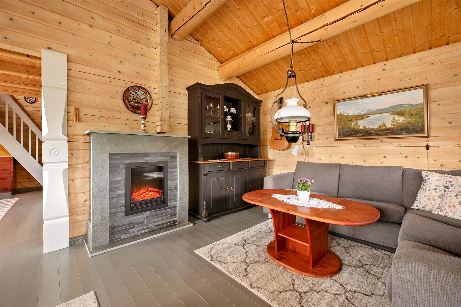 Stua har god takhøyde og åpen løsning mot kjøkken. Her ser du at de generøse stolpene er malt i hvitt. Elektrisk peis i stue og vedfyrt ovn på kjøkken. Galleribilde