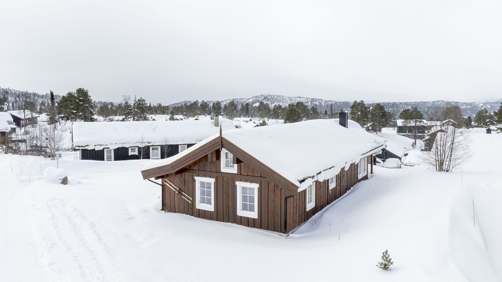 Fritidsbolig ligger på en romslig, flate tomt god plass og "luft" rundt bebyggelsen. Tomten har stor solterrasse på 2 sider, dels overbygget mot vest. Romslig gårdstun med meget god parkeringsplass, opparbeidet med skiferheller. Galleribilde