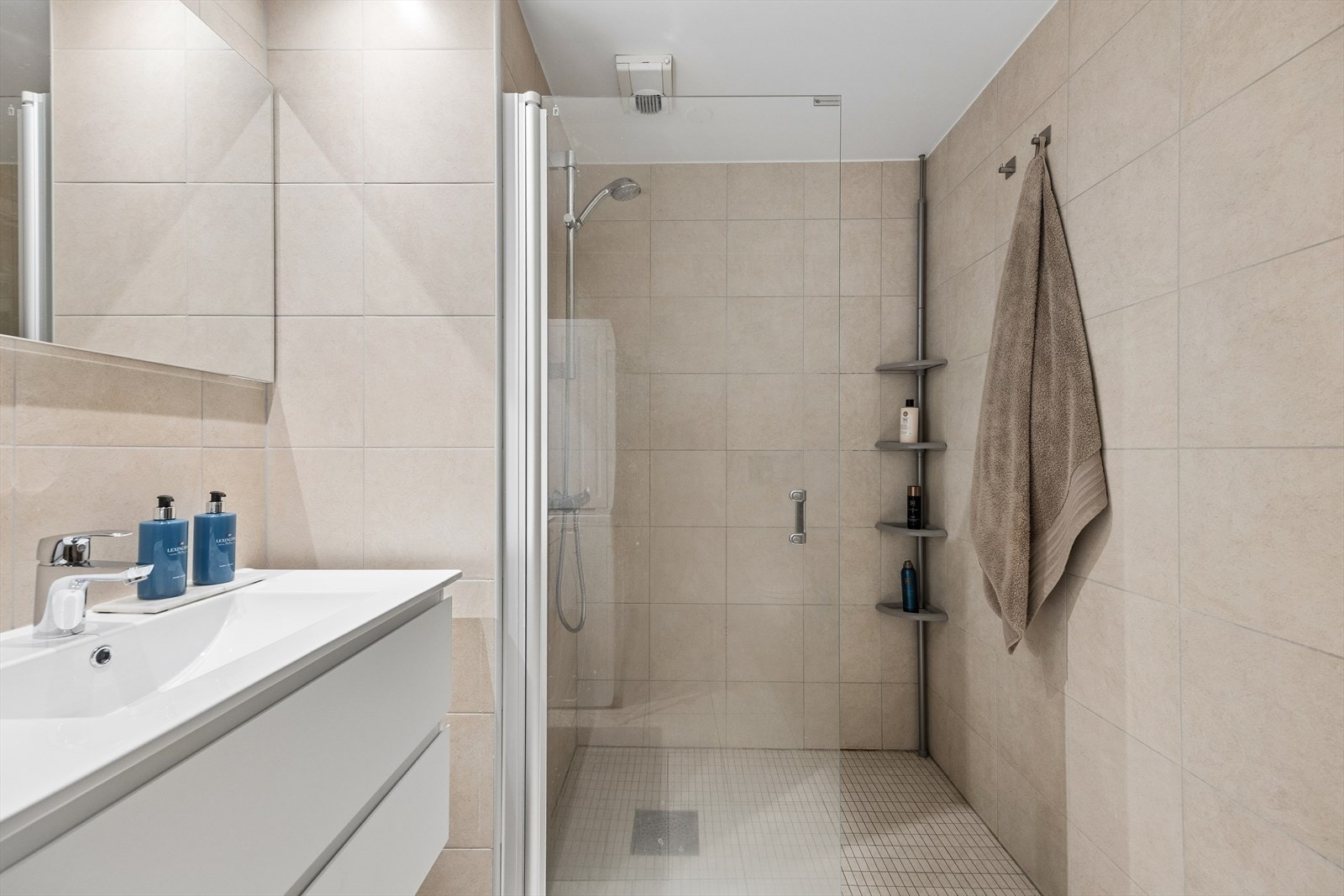 Flislagt bad med en nyere servantinnredning og et praktisk dusjhjørne med innfellbare glassvegger. Galleribilde