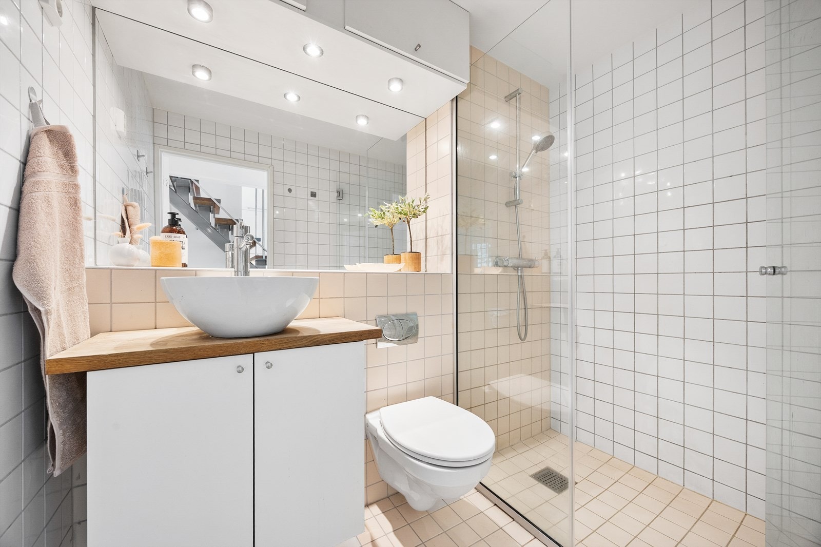 Flislagt bad med gulvvarme. Badet er utstyrt med "skål" servant med skap under, dusjsone og vegghengt toalett. Galleribilde