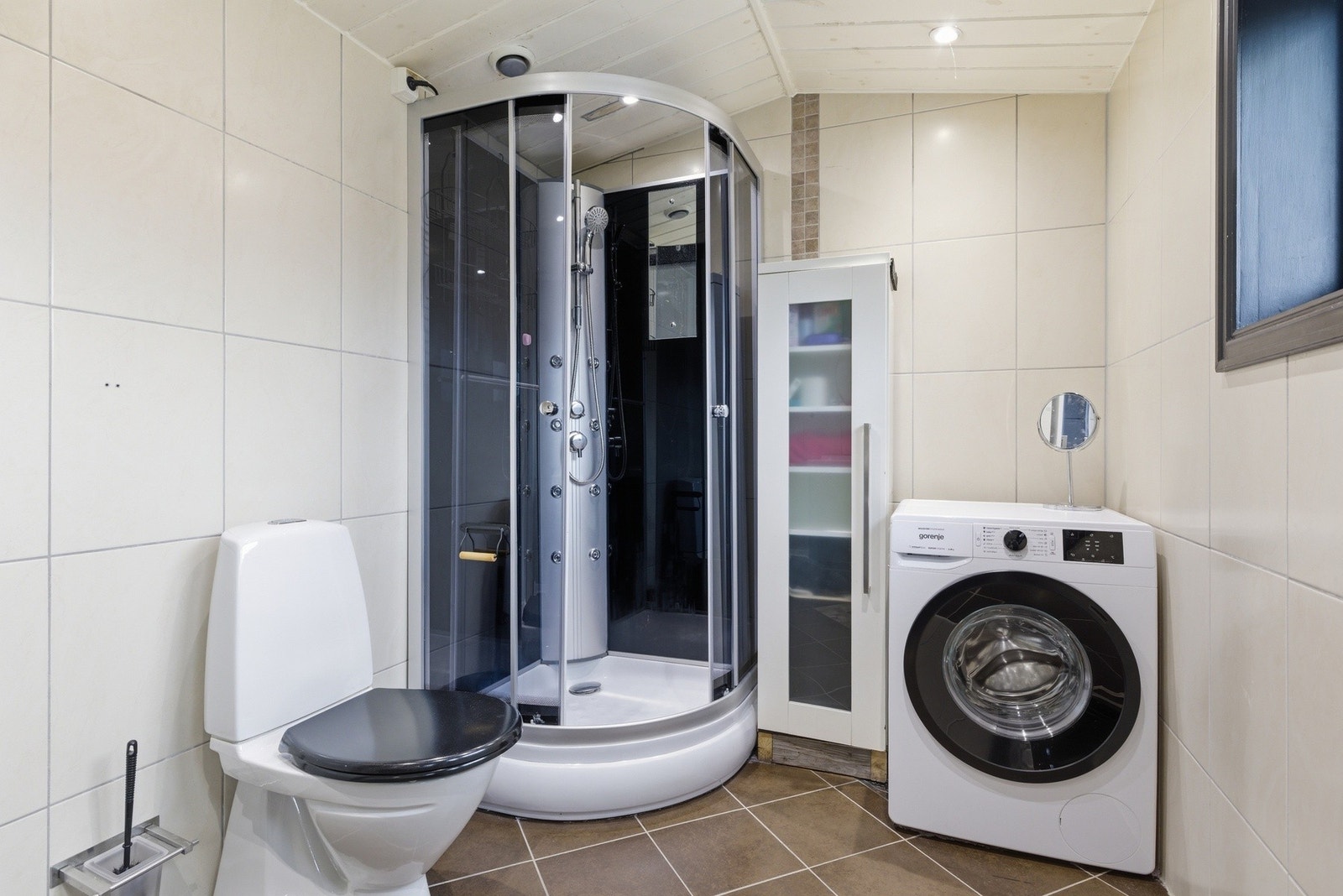 Flislagt bad med varmekabler. Badet er innredet med dusjkabinett, toalett, dobbel servant og opplegg til vaskemaskin. Galleribilde