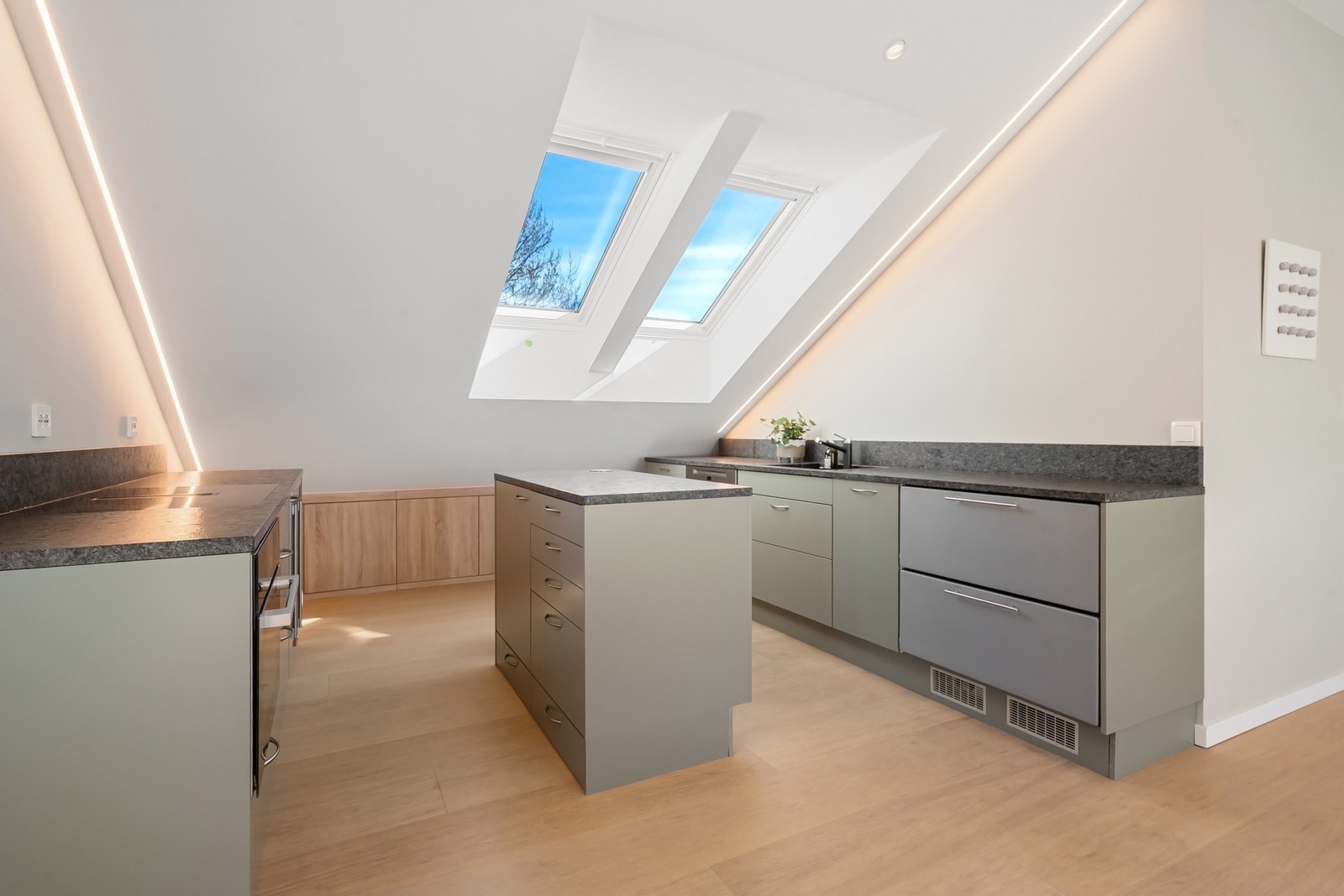 Moderne og stilrent kjøkken med plassbygde skapseksjoner, LED-lyslister og benkeplater i Silestone. Galleribilde