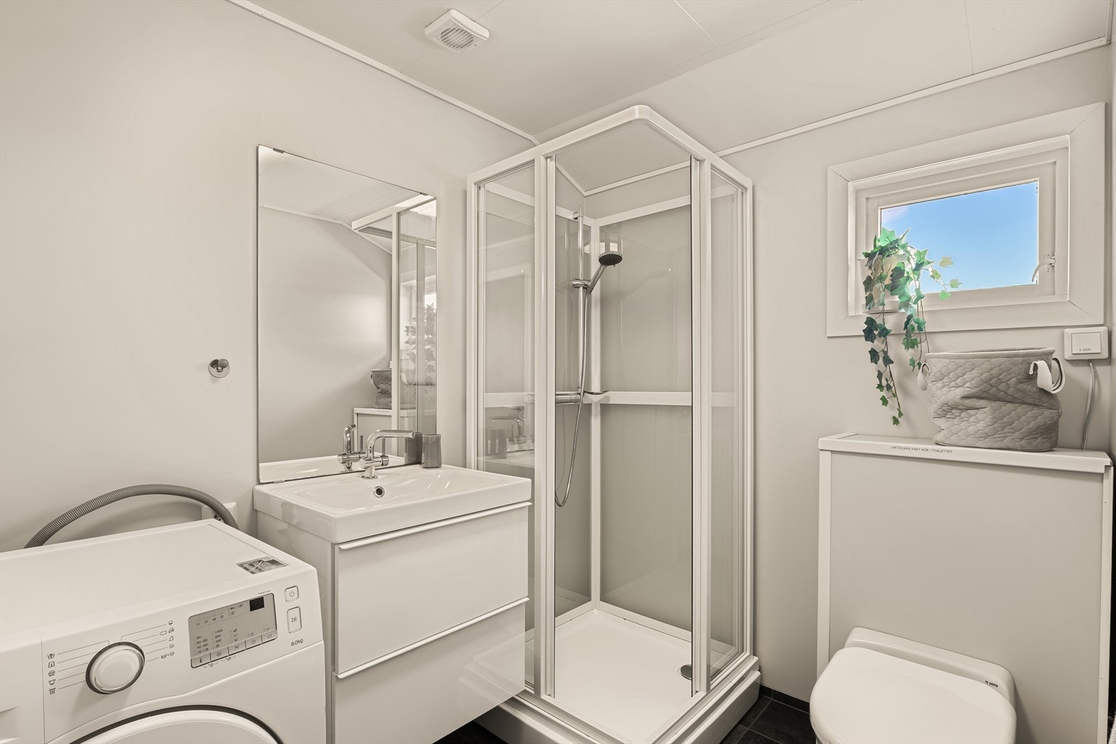 Badet har fliser på gulv og baderomsplater på vegger. Badet er innredet med baderomsinnredning med servant, disjkabinettm Jets toalett og opplegg for vaskemaskin. Galleribilde