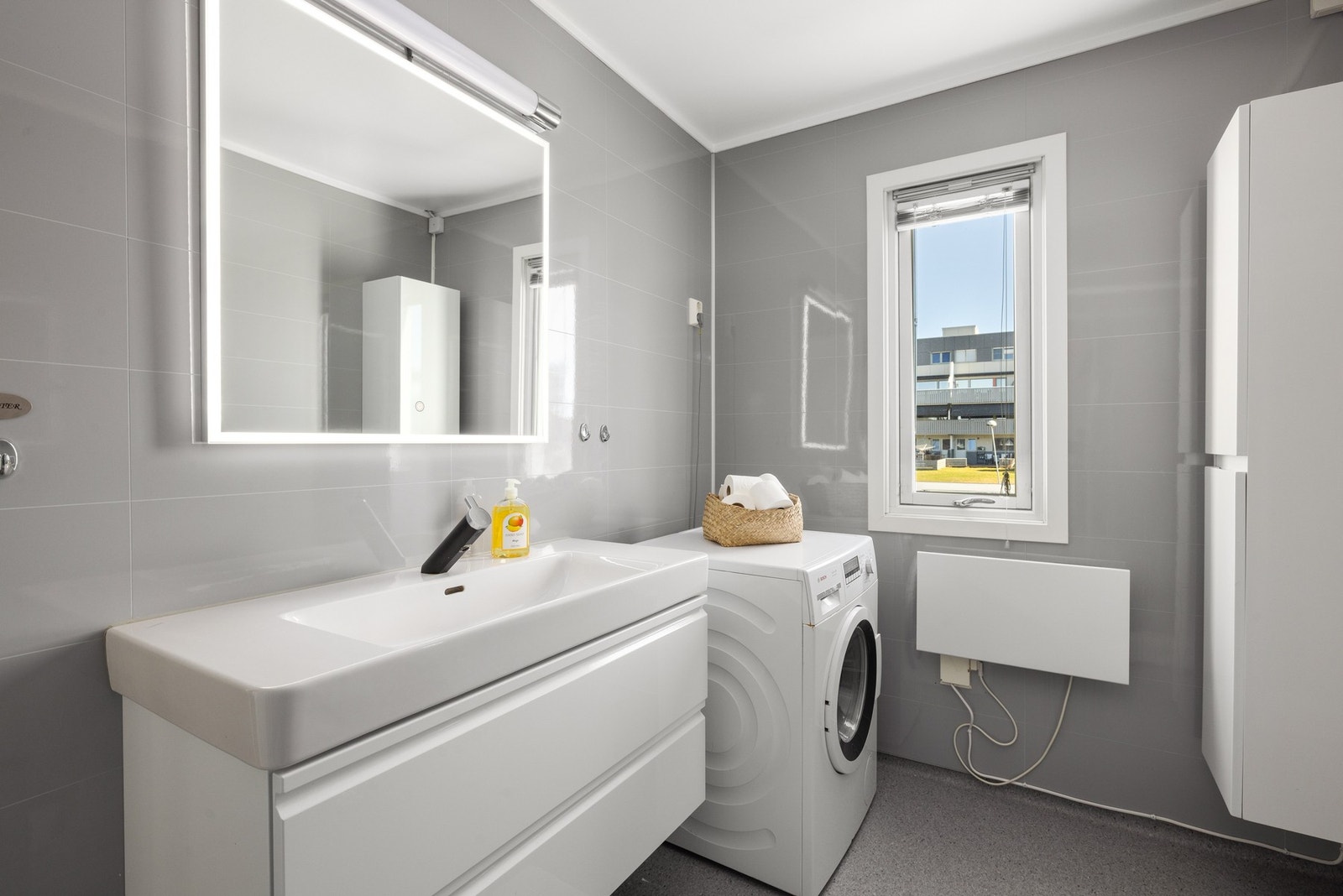 Lyst bad med opplegg for vaskemaskin og gode oppbevaringsmuligheter. Galleribilde