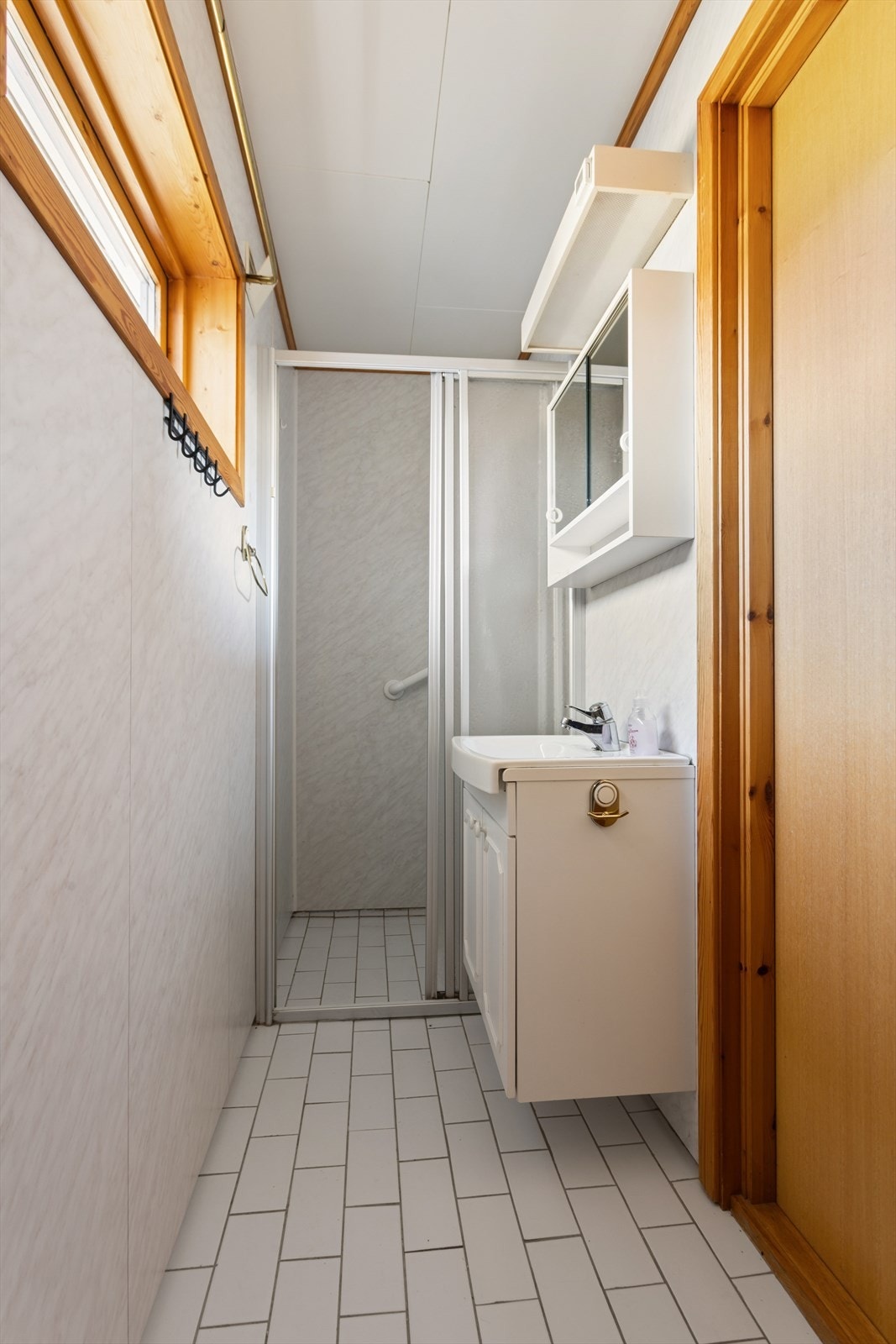 Badet er praktisk innredet med servant, toalett og en dusjnisje med skyvedør. Galleribilde
