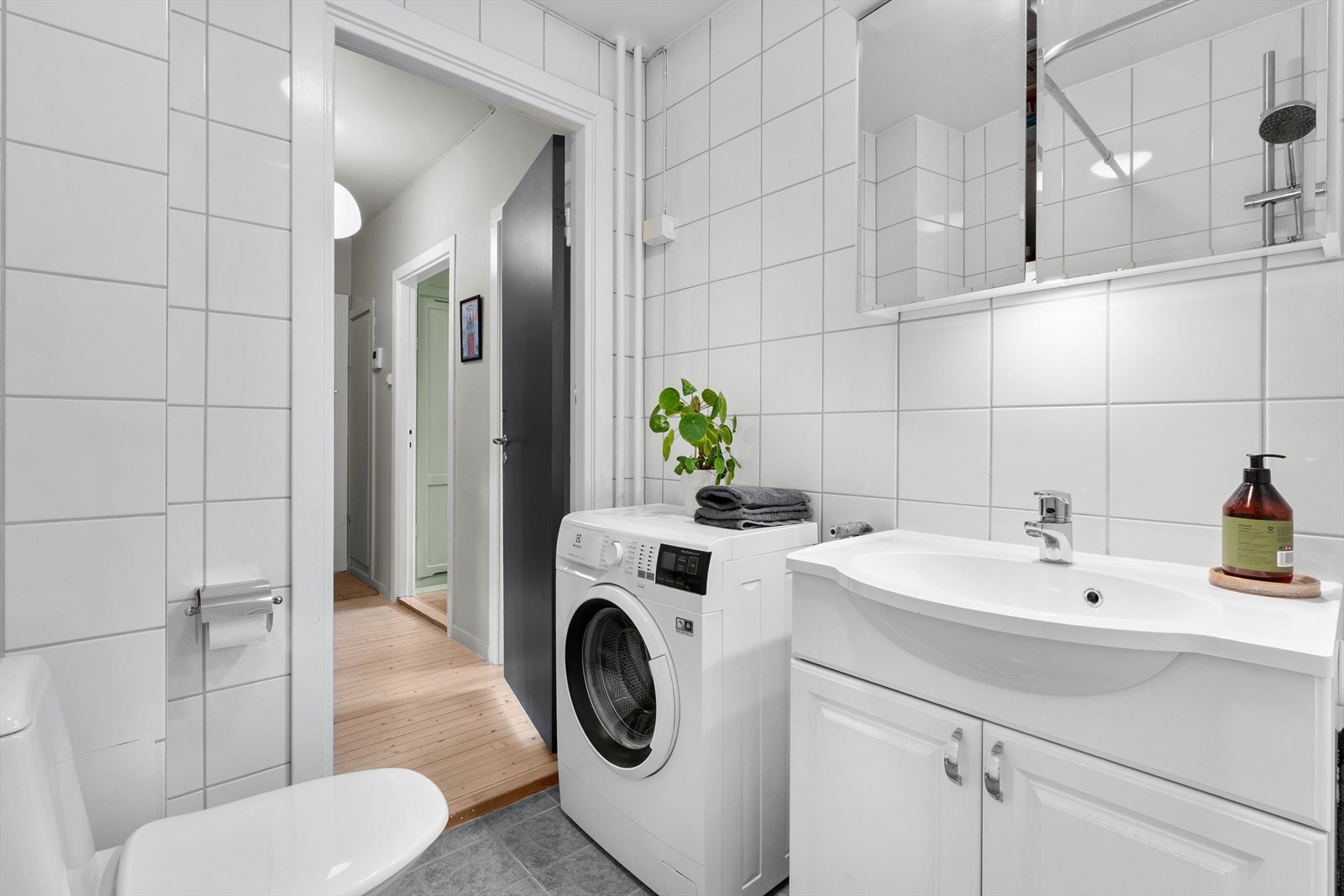 Badet er innredet med klosett, servant nedfelt i innredning, speilskap med lys og dusjhjørne med forheng. Galleribilde