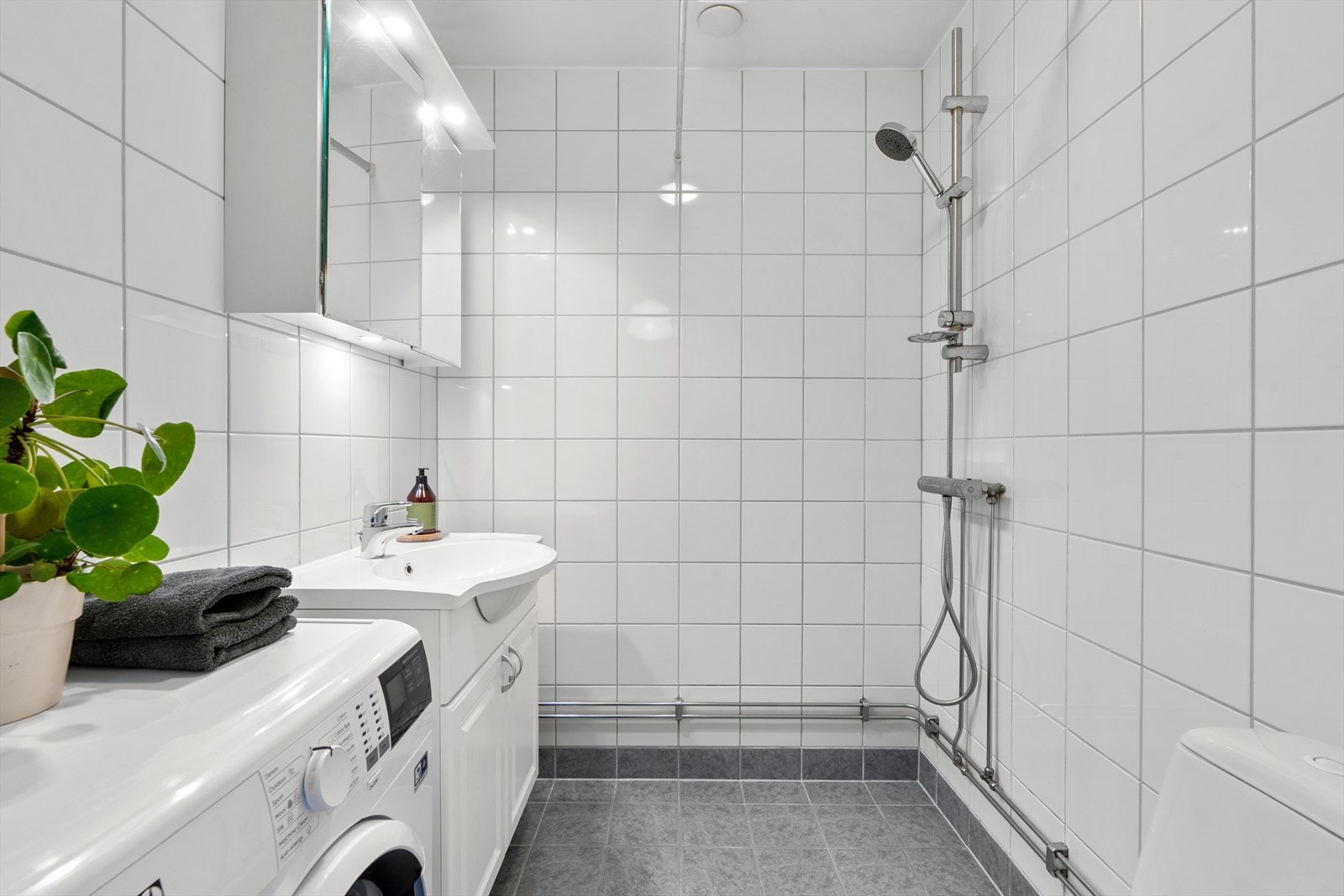 Pent flislagt baderom med elektrisk gulvvarme og opplegg for vaskemaskin. Galleribilde