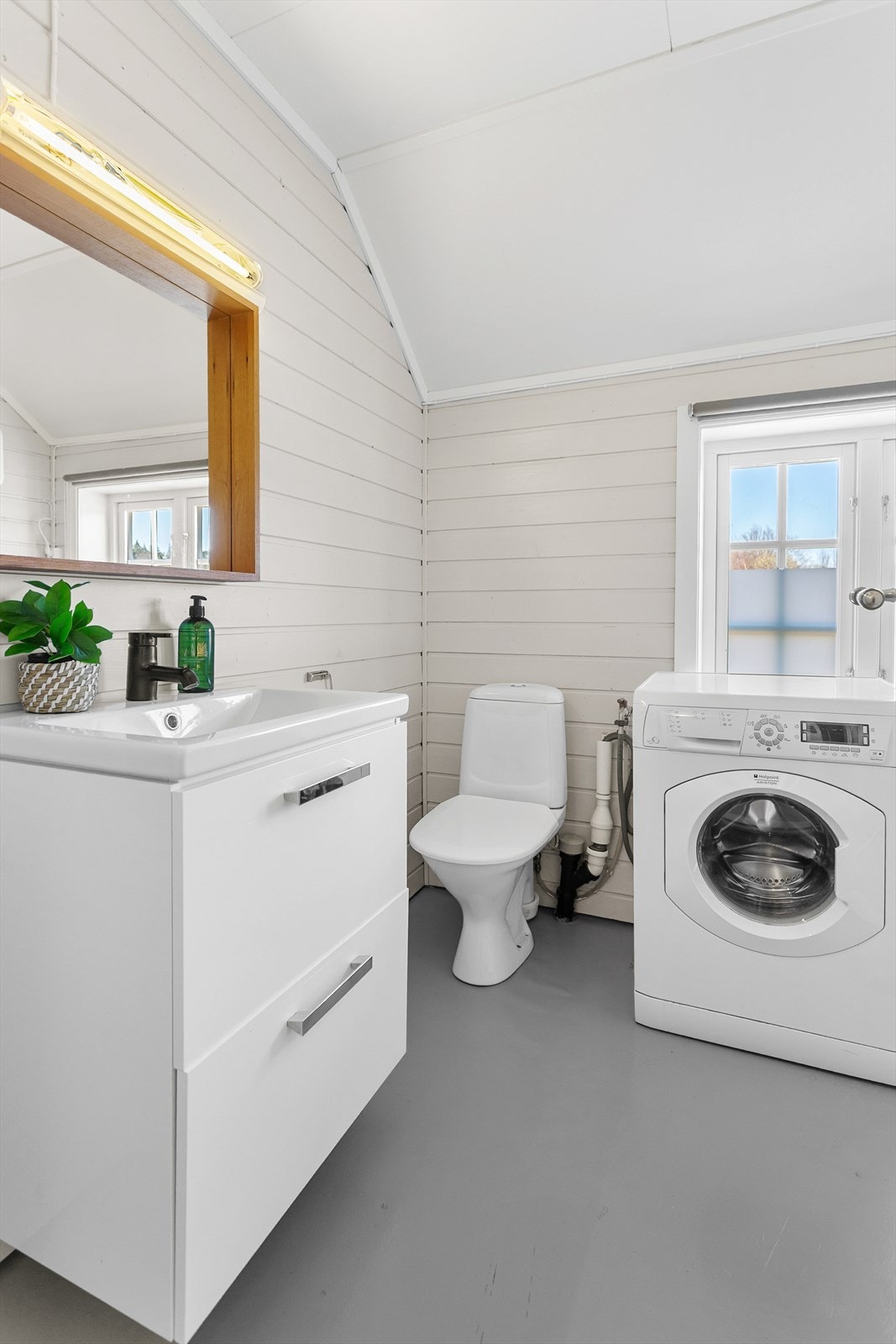 Badet er innredet med vinylbelegg på gulvet og malt panel på veggene, og er utstyrt med toalett, servant og opplegg for vaskemaskin. Galleribilde