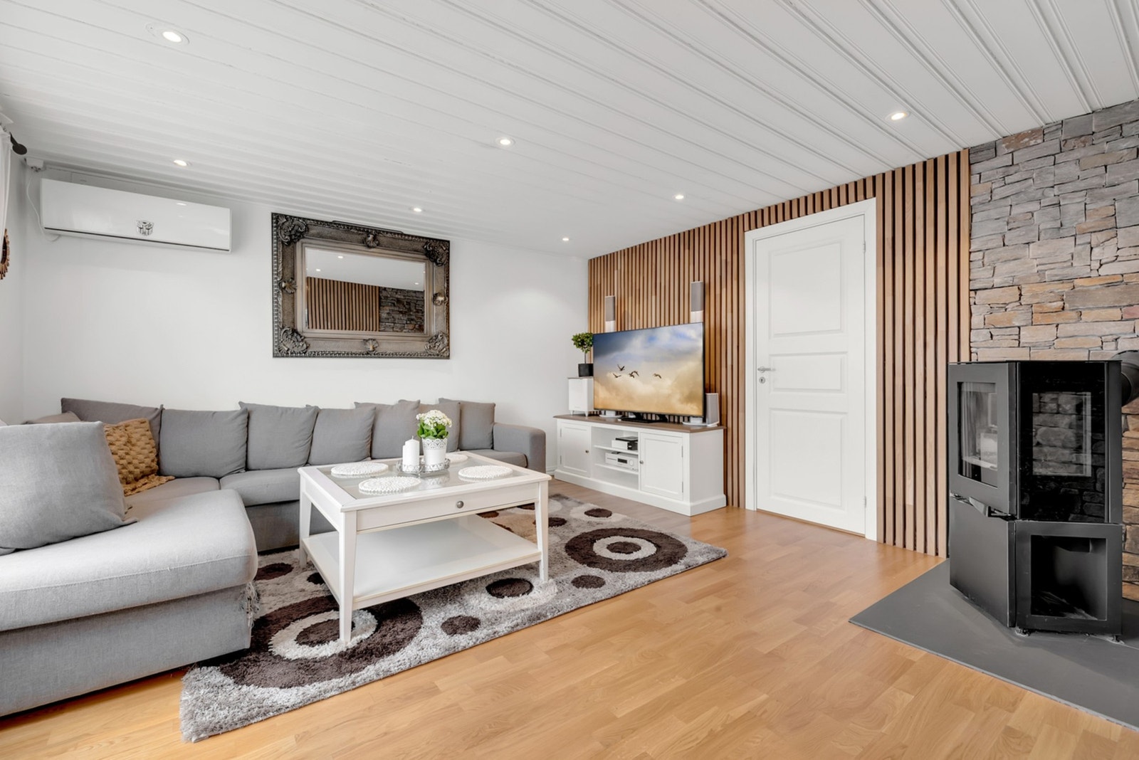 Stuen byr på god plass til sofa, TV-møblement og et hyggelig ildsted som skaper lun atmosfære. Galleribilde