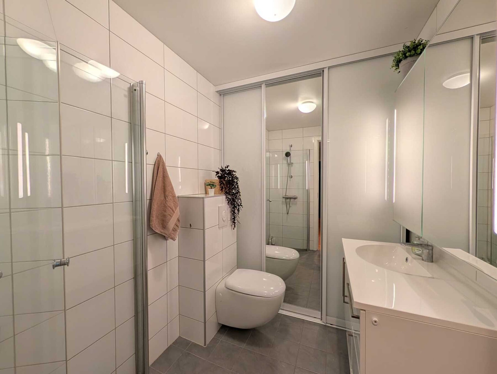 Fra entréen er det direkte adkomst til badet, som er helfliset med slett, malt tak. Galleribilde