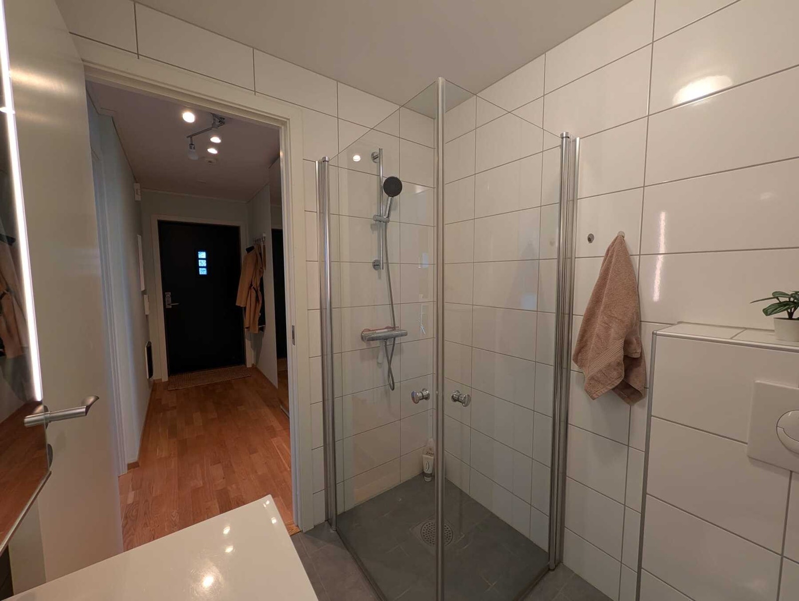 Badet har innfelte downlights i himling og varmekabler i gulv. Rommet er innredet med dusj med glassvegger, vegghengt toalett og baderomsinnredning. Galleribilde