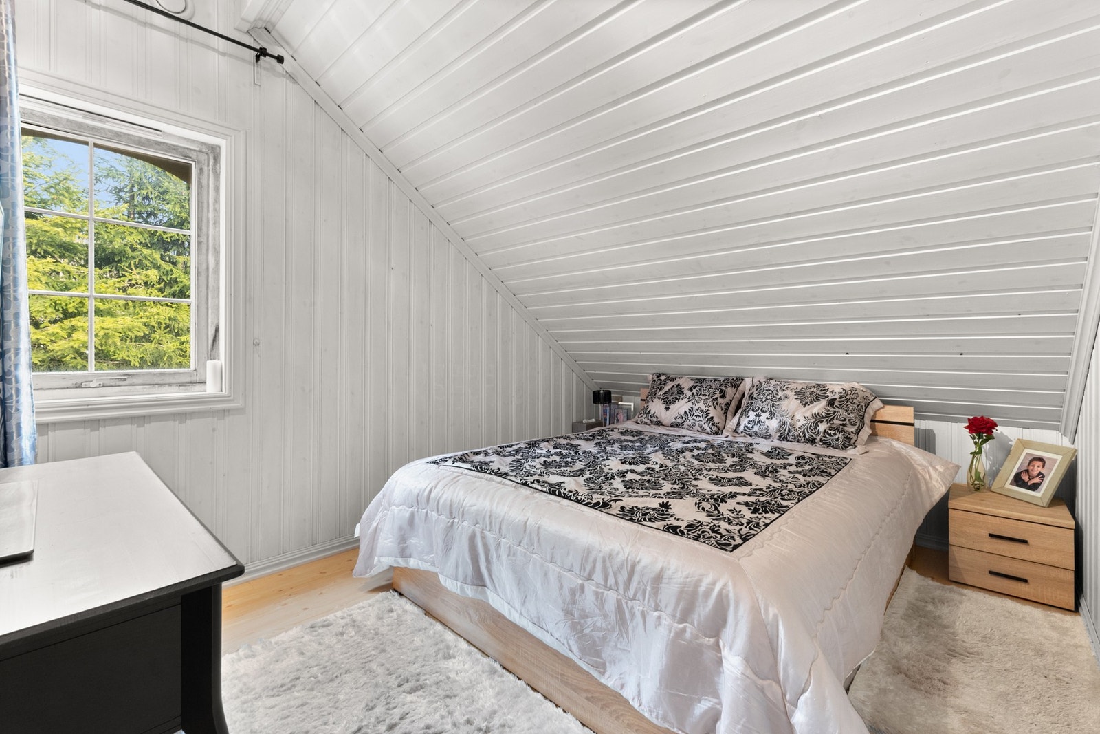 Lunt og innbydende soverom med skråtak og plass til dobbeltseng samt tilhørende møblement. Galleribilde