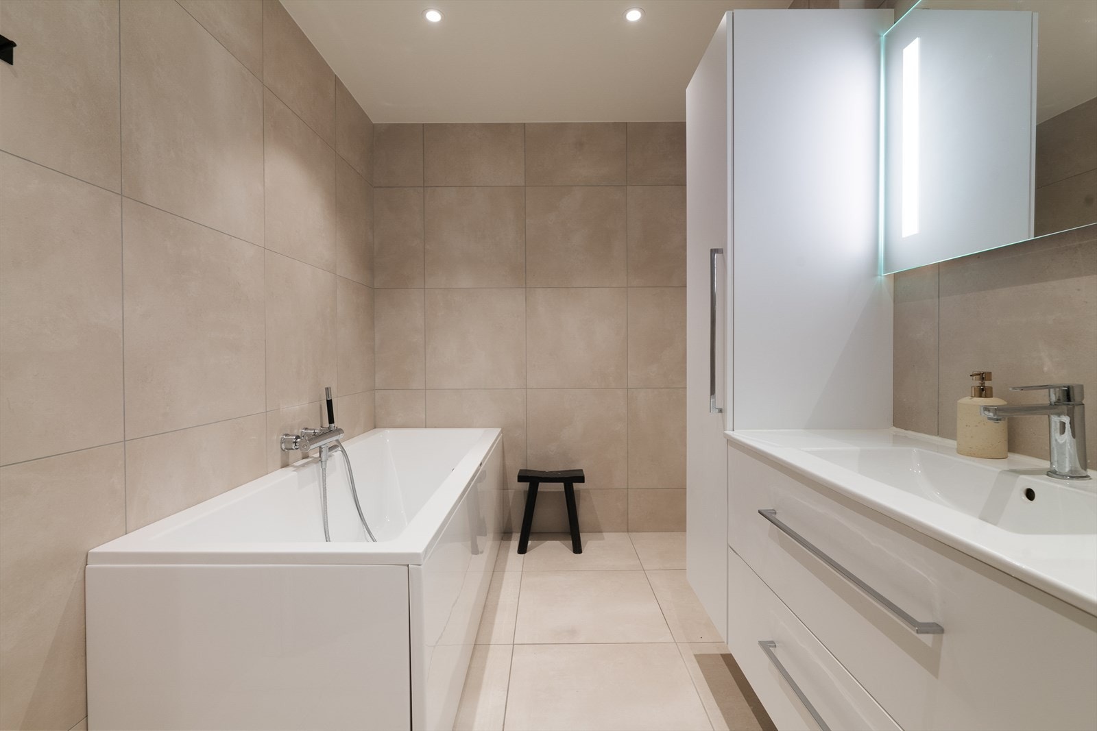 Badet er innredet med heldekkende servant med underskap, høyskap, speil med lys, vegghengt toalett, dusjhjørne og badekar. Galleribilde