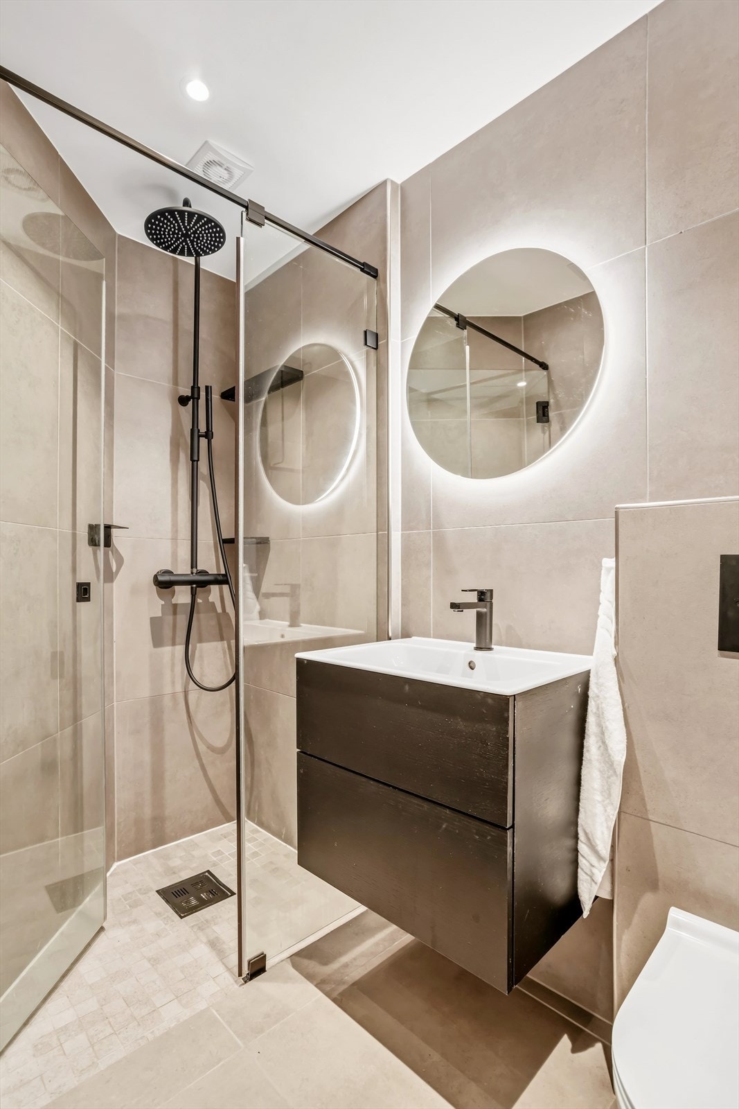Badet består av servant på benkeskap med glatte fronter, speil og belysning over servant, dusj med faste felt og dør i herdet glass, samt veggfestet klosett med innebygget sisterne. Galleribilde