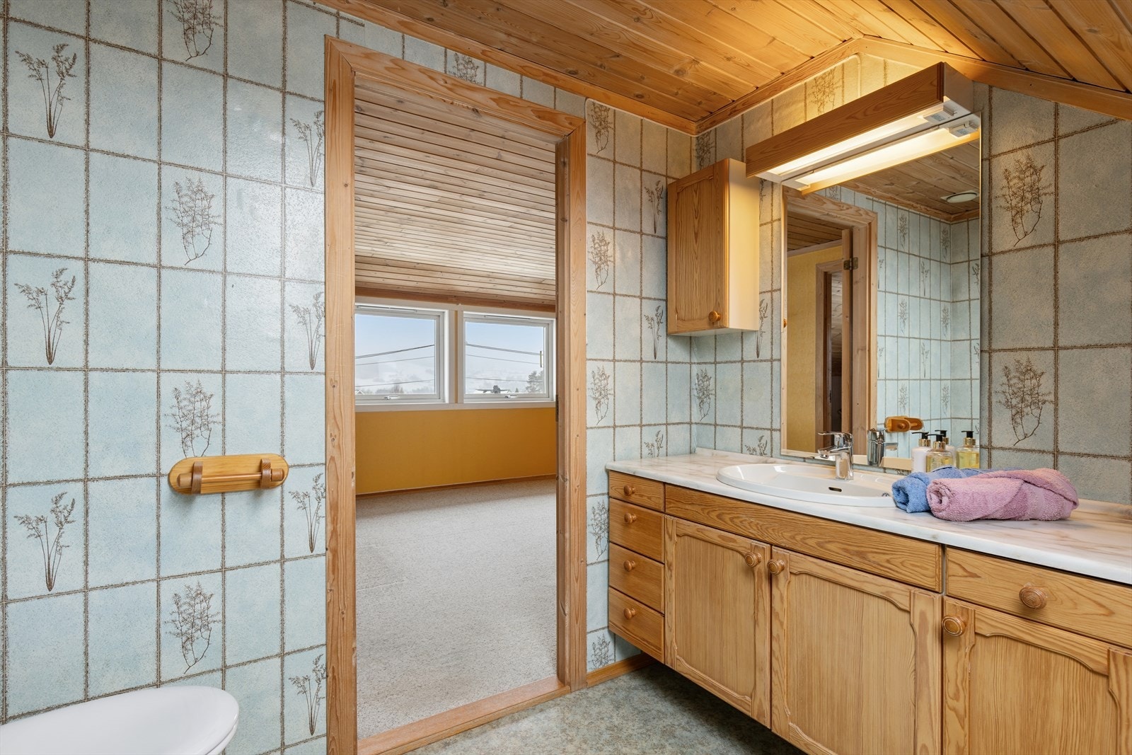 Toalettrom i 2. etasje med vinylbelegg på gulv og vinyltapet på vegger og panelovn som oppvarmingskilde. Innredet med servantinnredning og wc. Galleribilde