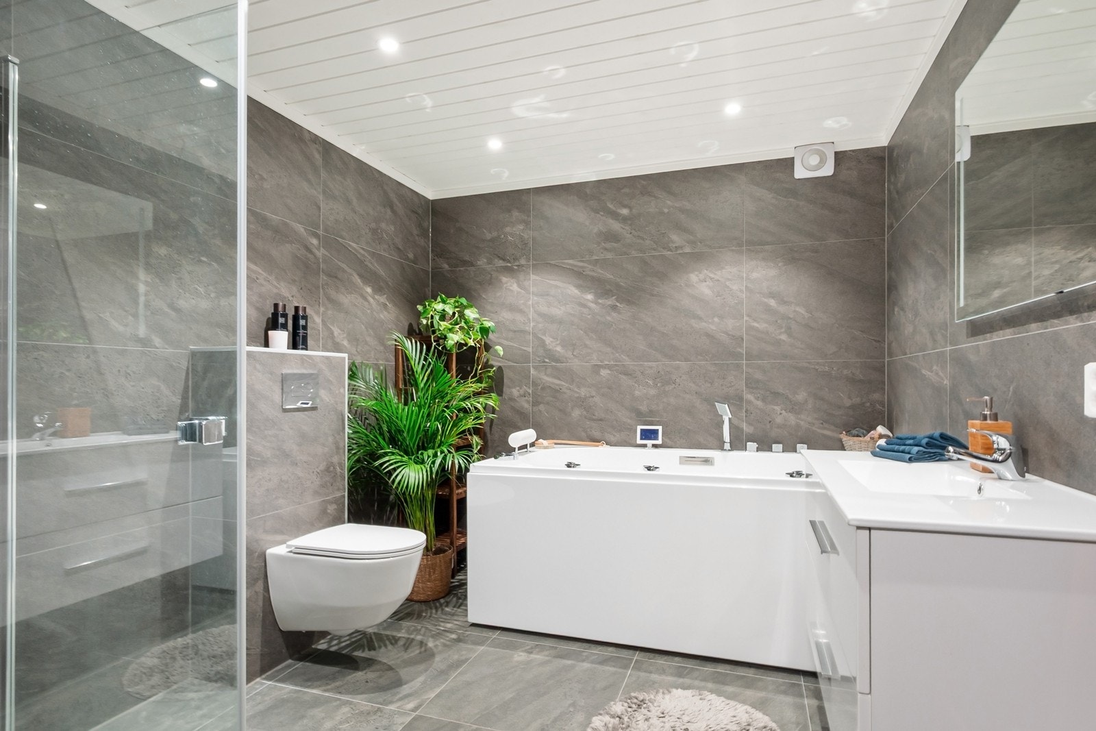 Badet i kjelleretasjen ble pusset opp i 2021. Rommet har store 60x60 fliser på gulv og vegger, gulvvarme og downlights i himling. Innredningen består av nedfelt servant, vegghengt toalett og massasjebadekar Galleribilde