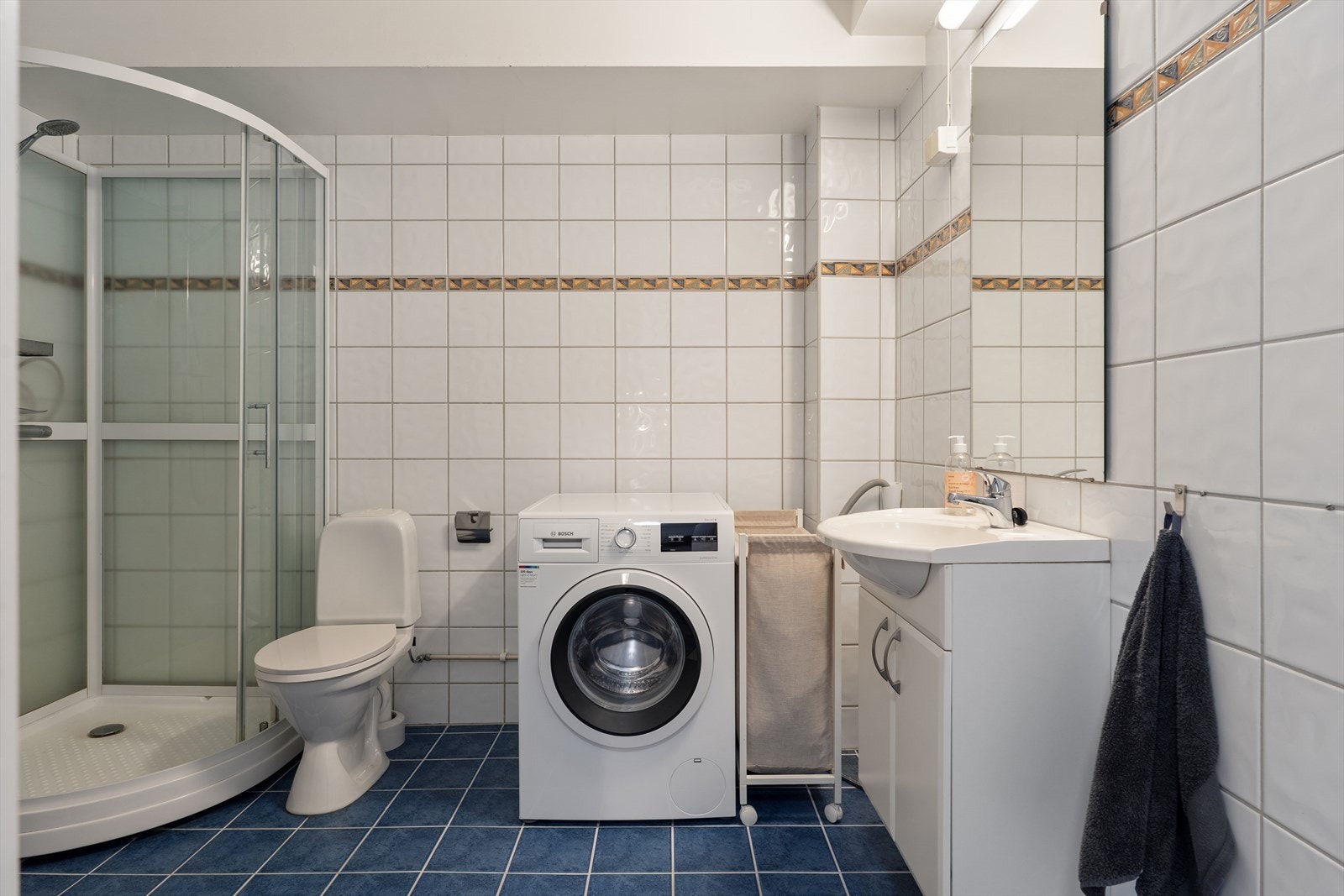 Badet er utstyrt med dusjkabinett, gulvstående toalett og opplegg for vaskemaskin. Galleribilde