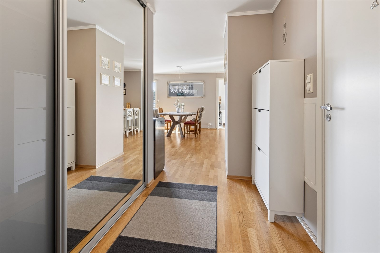 Entréen gir et innbydende førsteinntrykk med gjennomgående parkettgulv og god oppbevaringsplass i skyvedørsgarderobe. Leiligheten har vannbåren gulvvarme i alle rom, med unntak av badet som varmes opp med elektriske varmekabler. Galleribilde