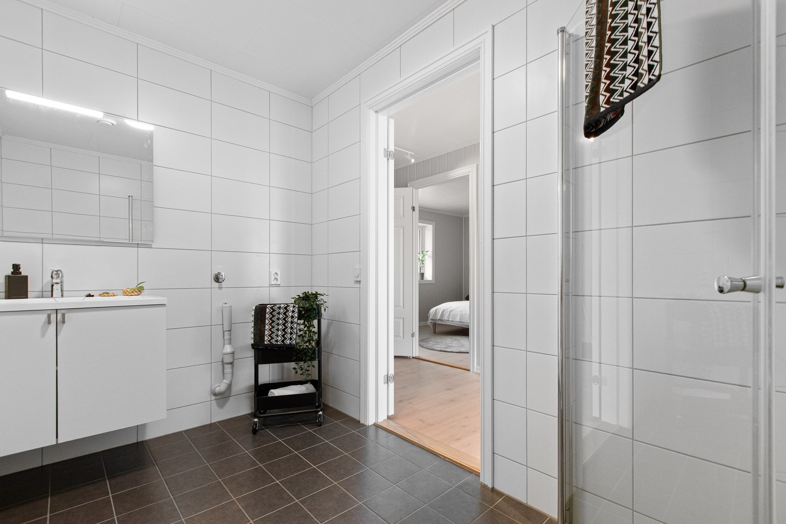 Flislagt bad med gulvvarme, vegghengt servantskap og opplegg for vaskemaskin. Galleribilde