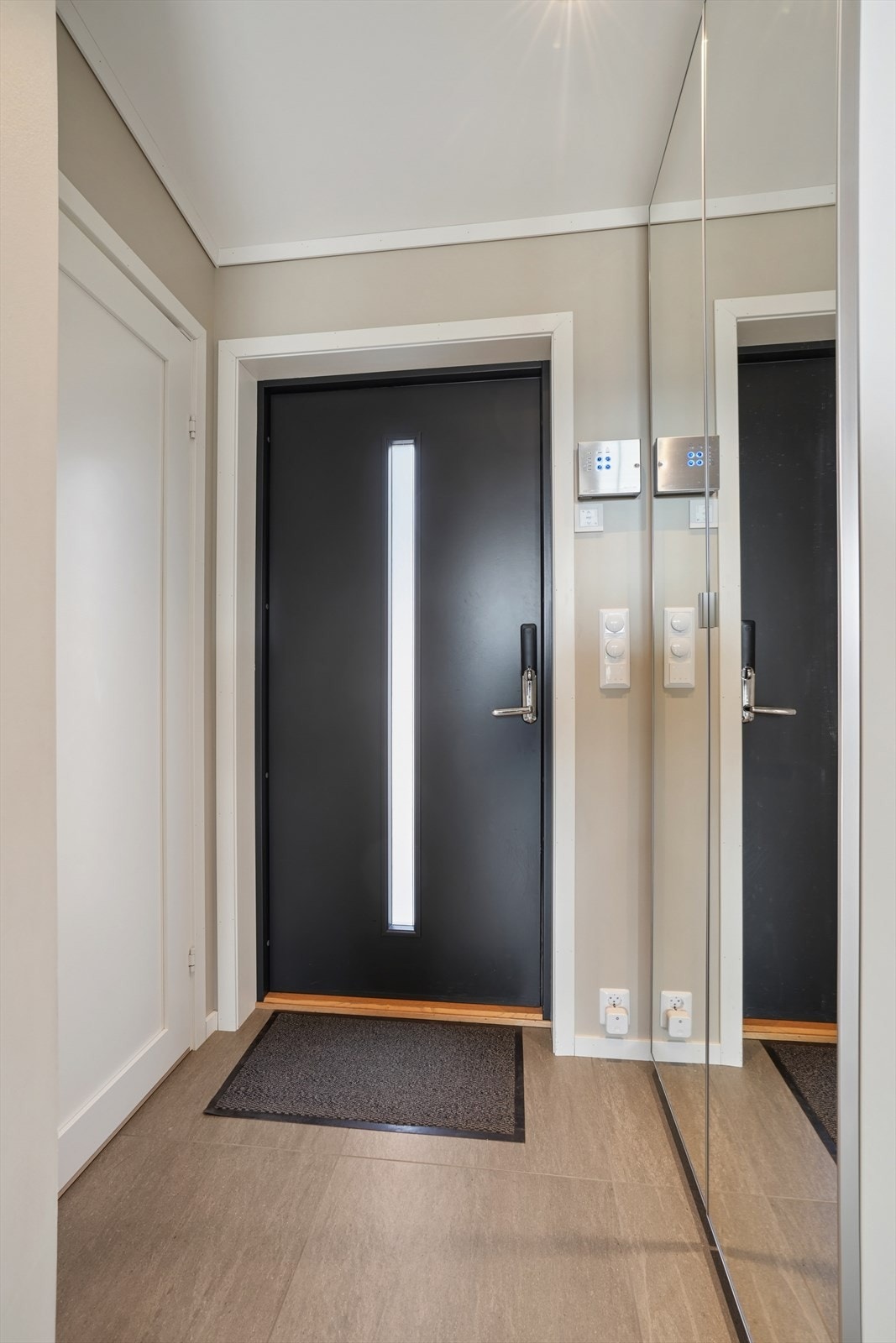 Velkommen inn! Entré med flislagt gulv og garderobeskap med speilfronter. Galleribilde