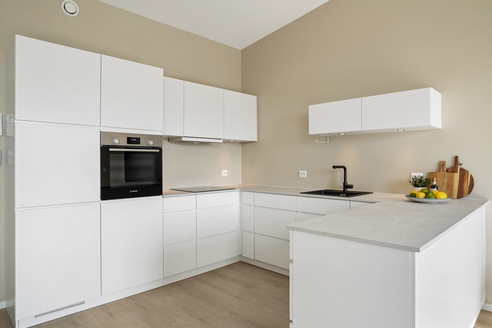Kjøkkeninnredning fra Kvik med slette fronter og laminatbenkeplate. Alle hvitevarer, inkludert integrert stekeovn, koketopp og oppvaskmaskin, medfølger. Galleribilde