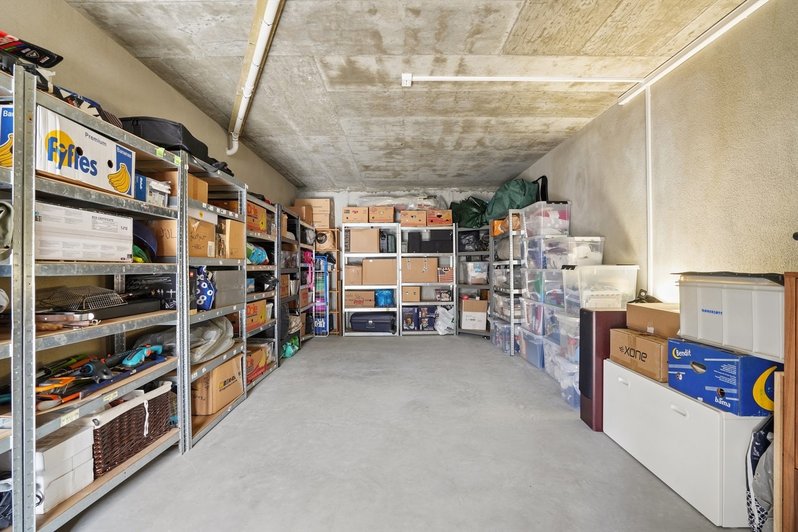 Svært romslig utebod på ca. 26 m² under garasjen, med støpt gulv og rikelig med lagringsplass. Her er også enheten til sentralstøvsugeren plassert. Galleribilde