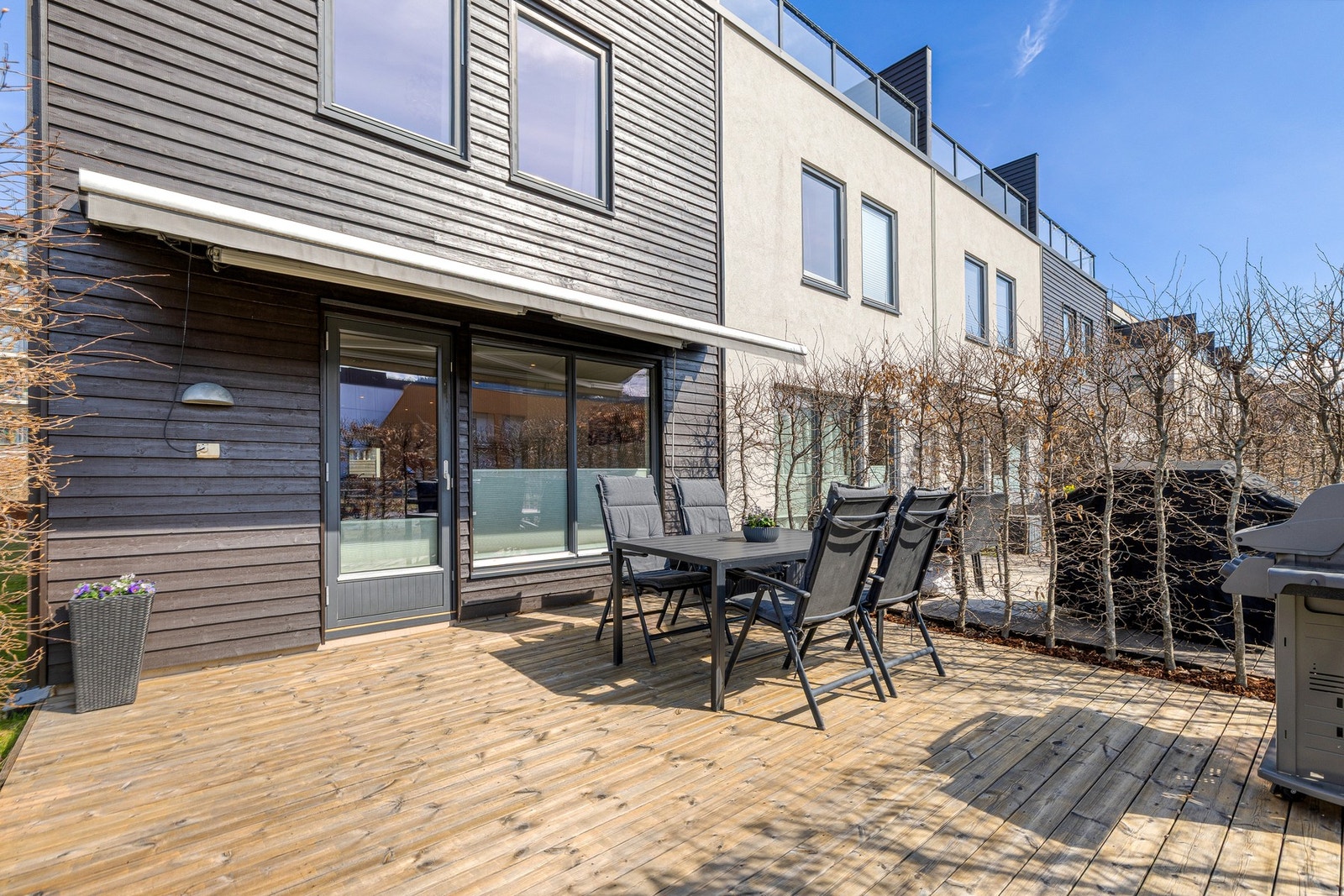 Terrasse med markise og grill, omkranset av hekk. Galleribilde