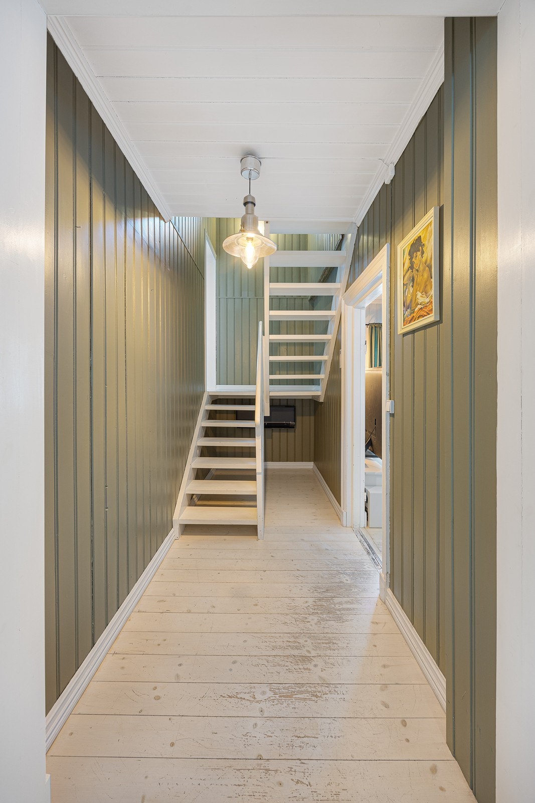 En hvitmalt trapp binder etasjene sammen. Under trappen er det en varmepumpe som bidrar til jevn, behagelig temperatur året rundt. Galleribilde