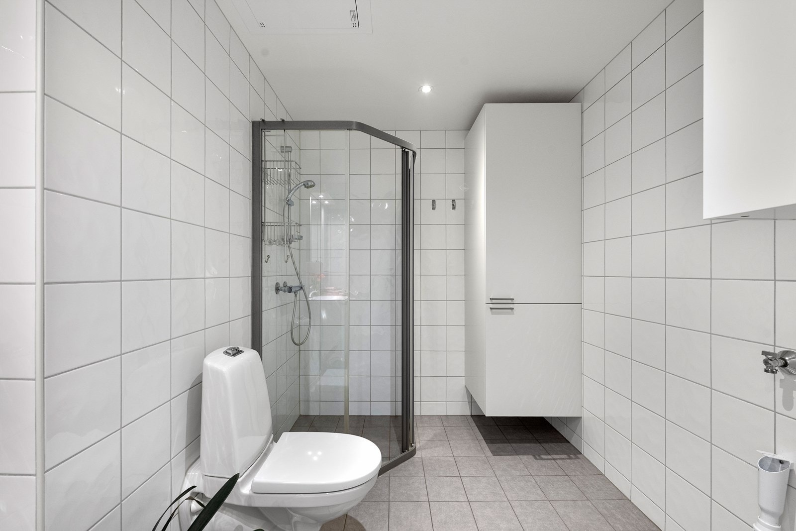 Badet er utstyrt med vegghengt toalett, dusjhjørne med glassvegger og opplegg for vaskemaskin. Galleribilde
