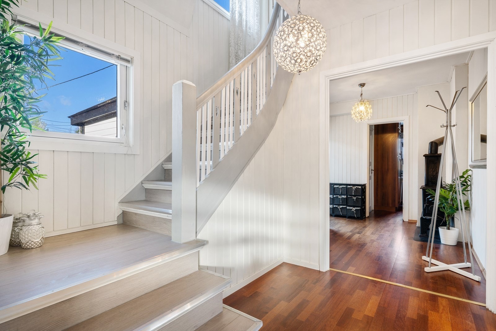 Innbydende entré med elegant trapp og store vinduer som slipper inn rikelig med naturlig lys. Galleribilde