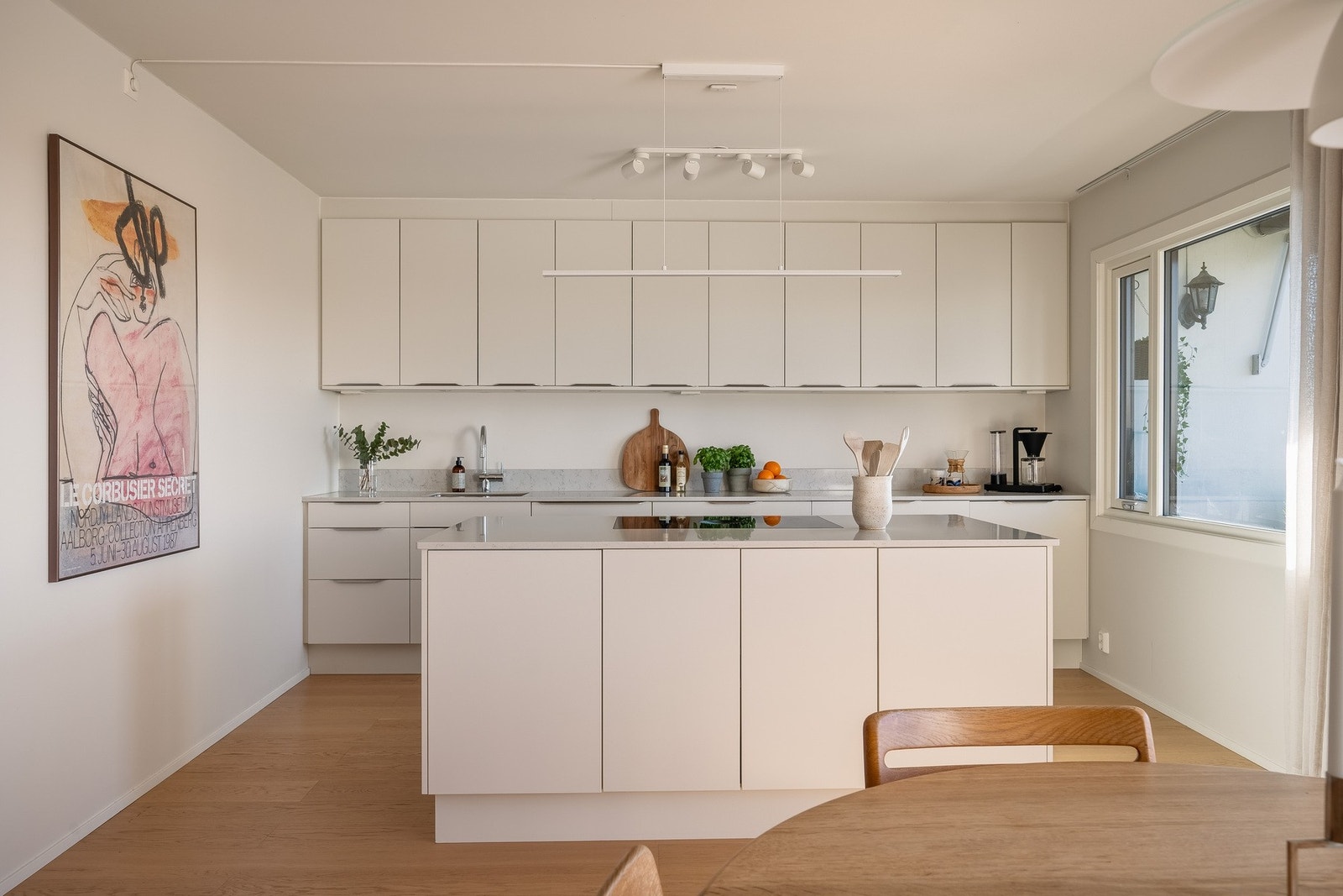 Glatte, hvite fronter er kombinert med benkeplate Silestone Lagoon kvarts og underlimt kum i stål, med oppbrett mot bakvegg som gir en praktisk løsning i daglig bruk. Galleribilde
