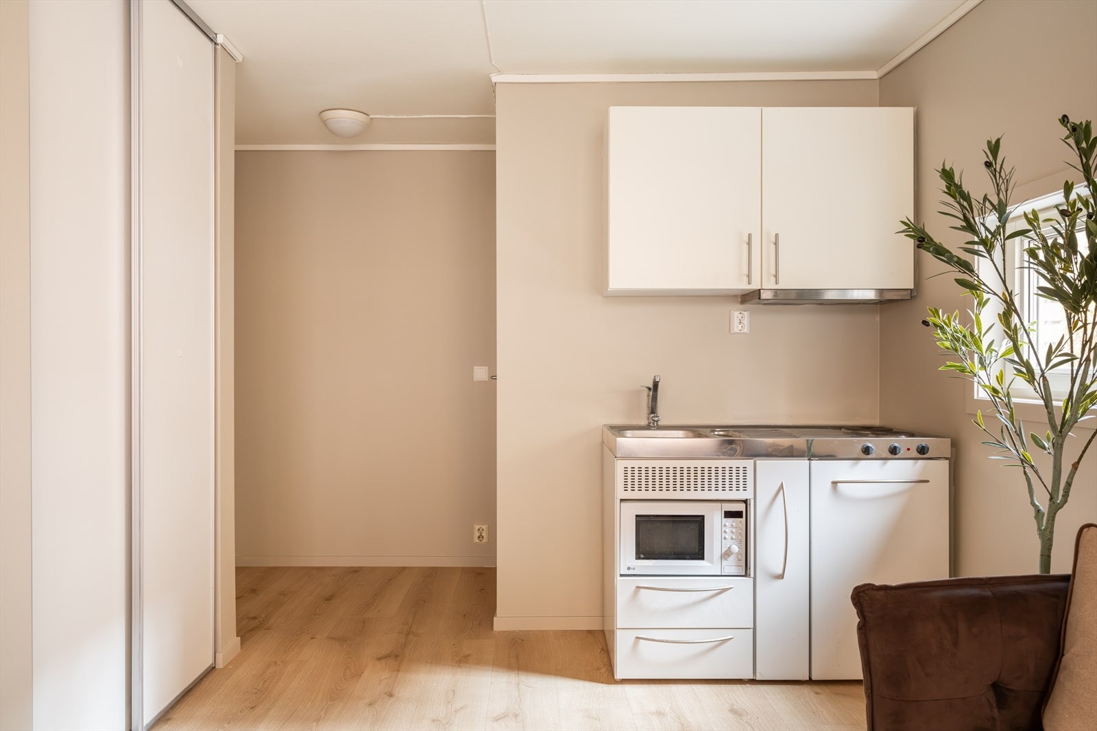 Pent kjøkken med glatte fronter og benkebeslag med vaskekum i rustfritt stål. Galleribilde