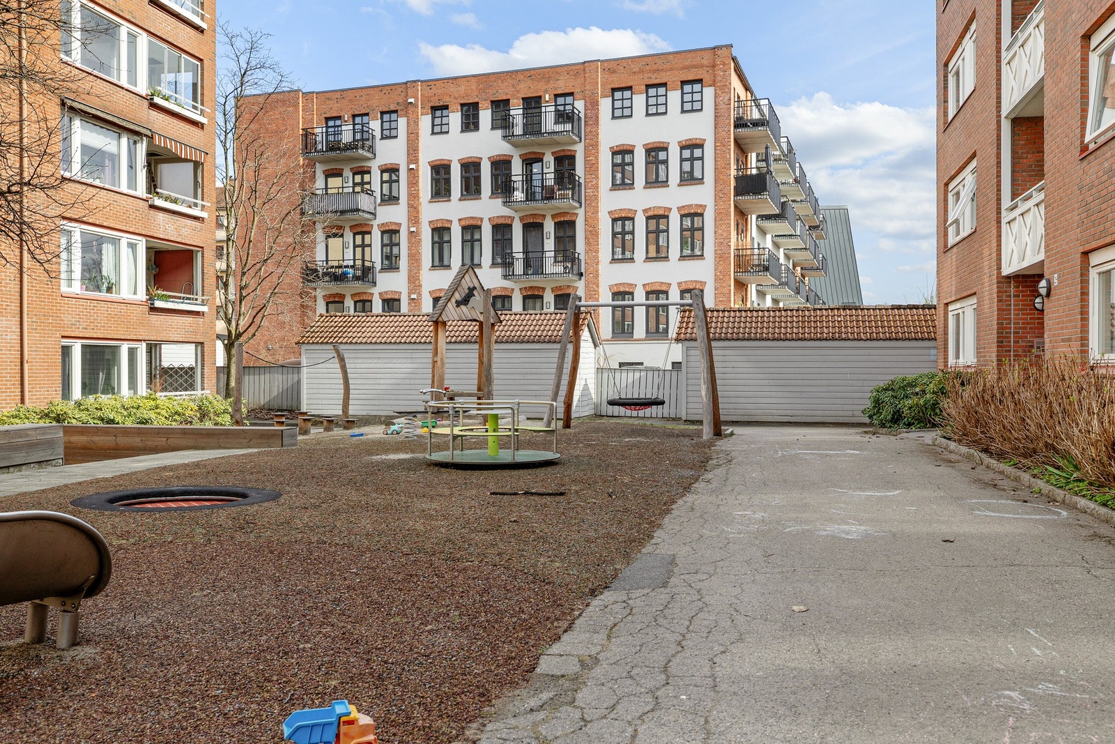 Hyggelig gårdsrom med asfalterte internveier, lekeplass og beplantning. Galleribilde