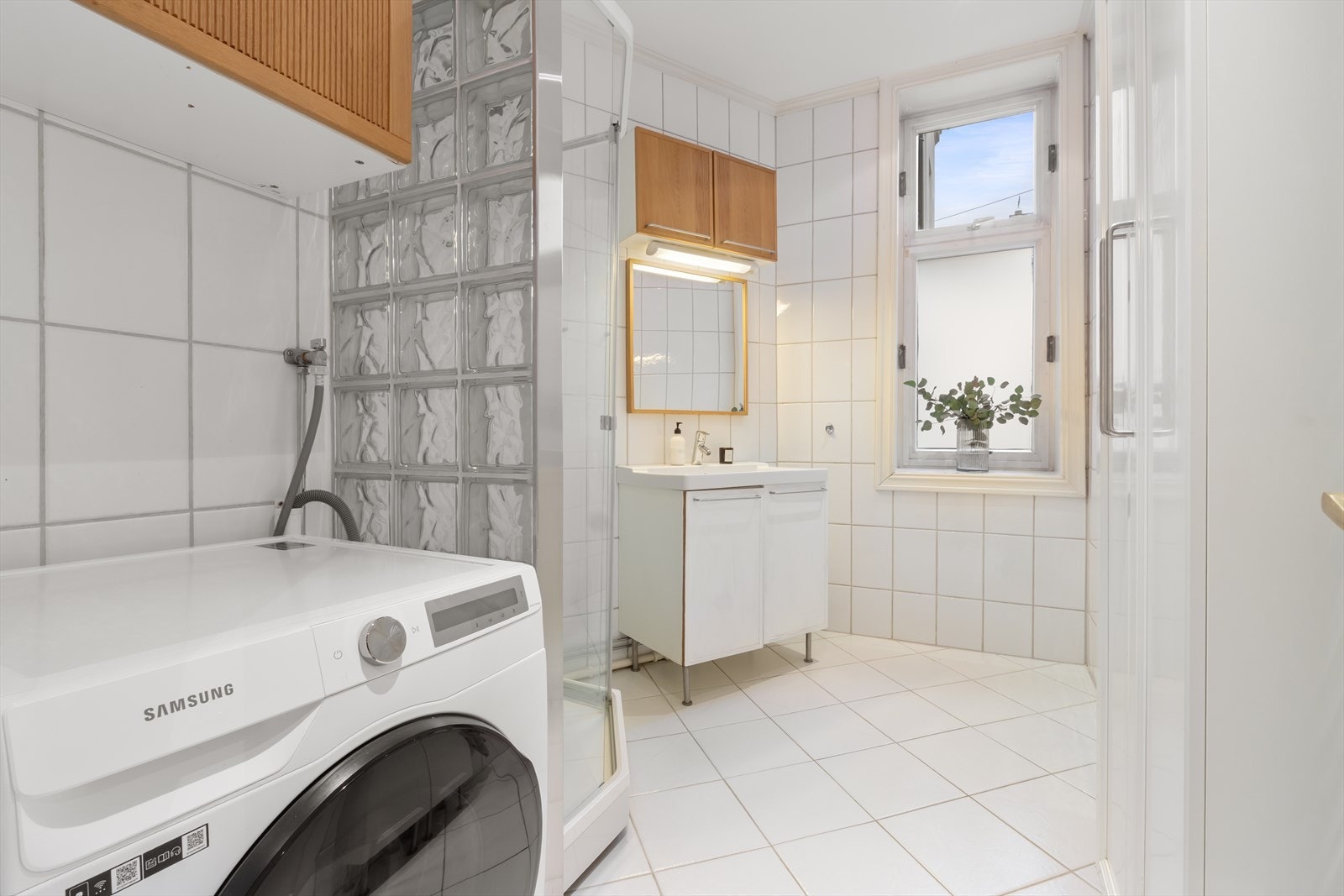 Stort og tidløst bad med flislagte overflater, gulvvarme og downlights i himling. Det er opplegg for vaskemaskin. Galleribilde