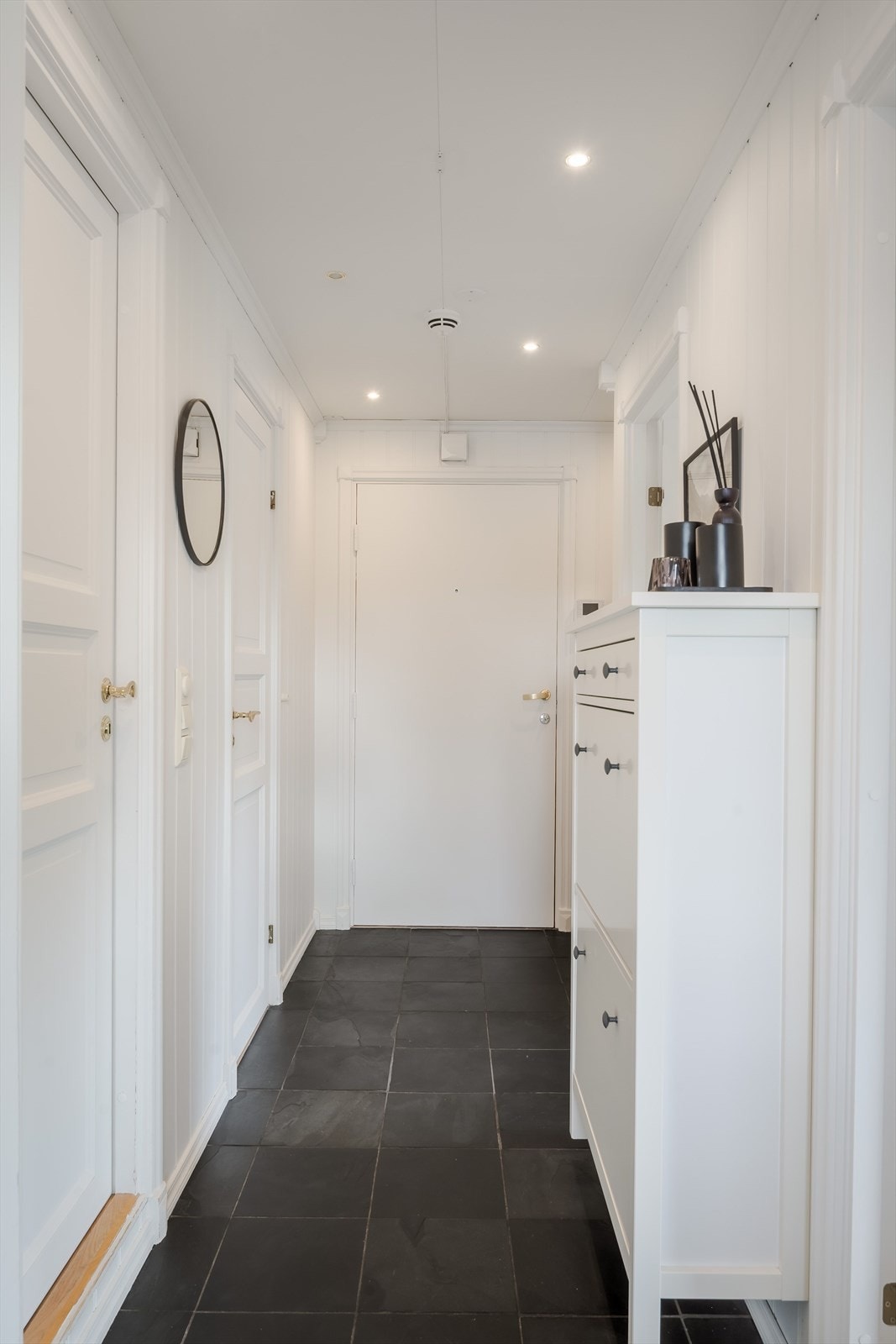 Entréen har mørke fliser på gulv, lysmalte overflater og downlights i himlingen. Galleribilde