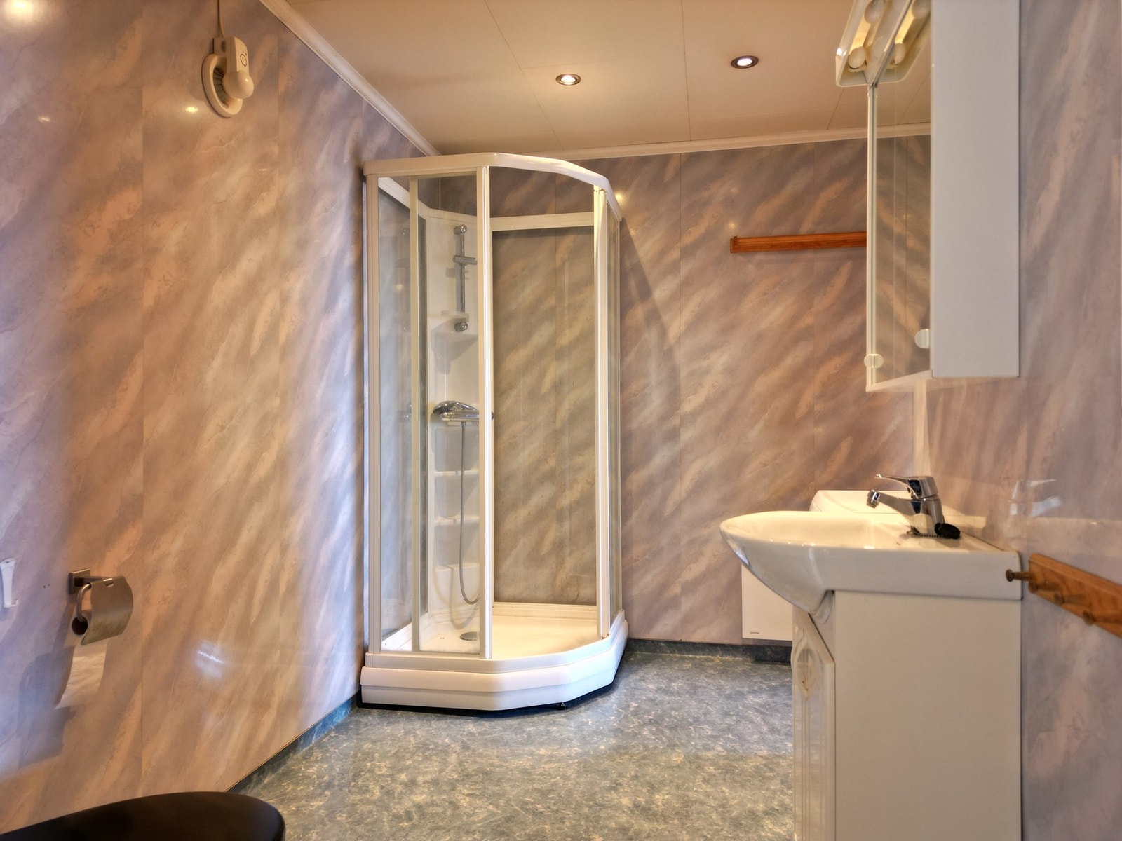 Badet har våtromsplater på vegg og belegg på gulv. Servantskap, dusjkabinett og toalett. Galleribilde