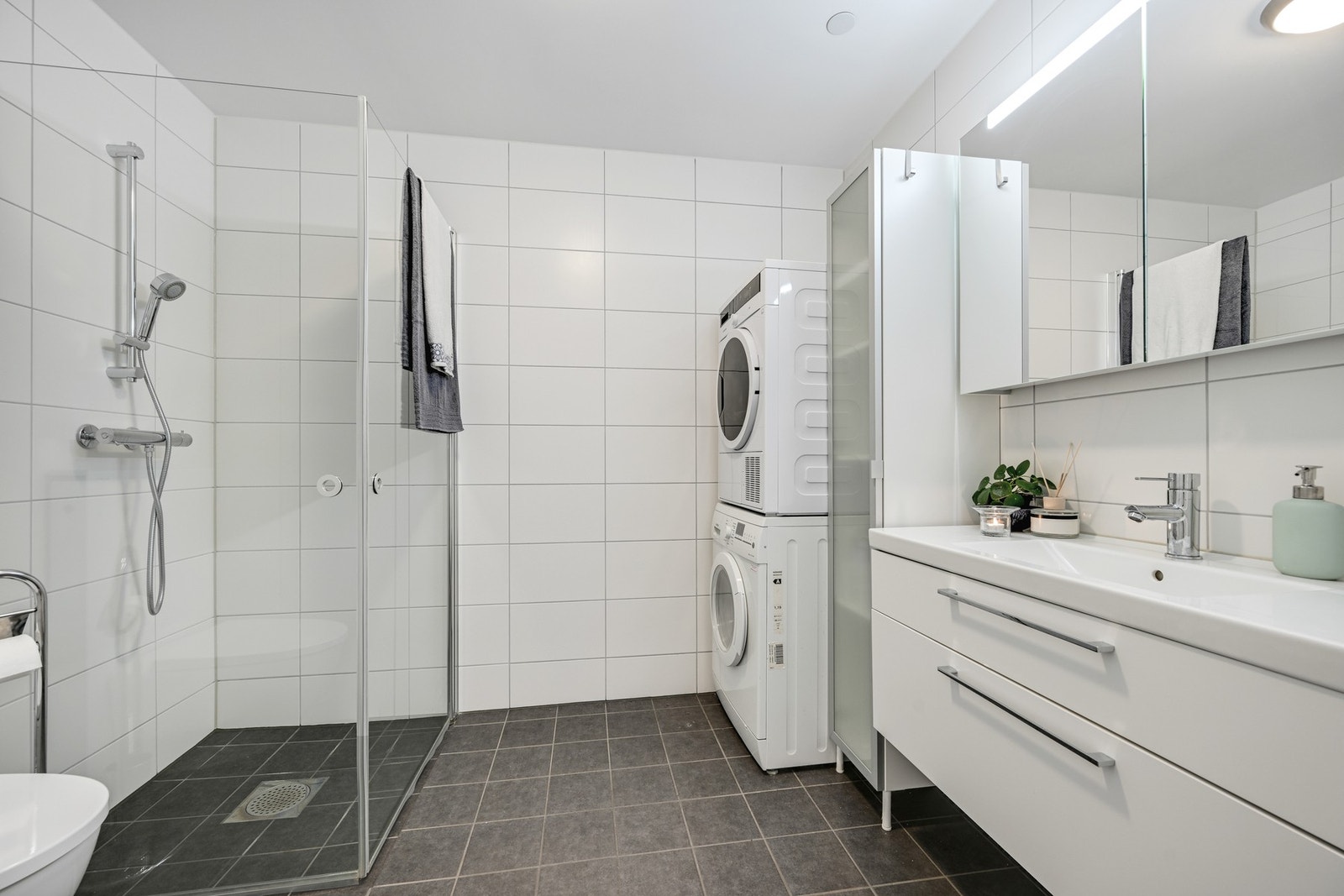 Hovedbadet er romslig og byr på dusjhjørne, klosett og en større innredning med overskap- og underskuffer. Det er god plass til vaskemaskin og tørketrommel Galleribilde