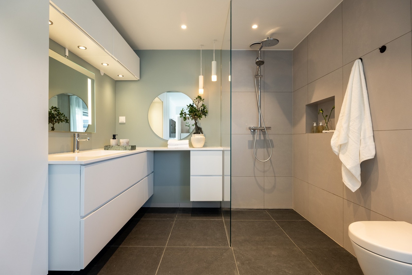 Badet har flislagt gulv og dusjsone, samt gulvvarme og downlights i taket. Galleribilde