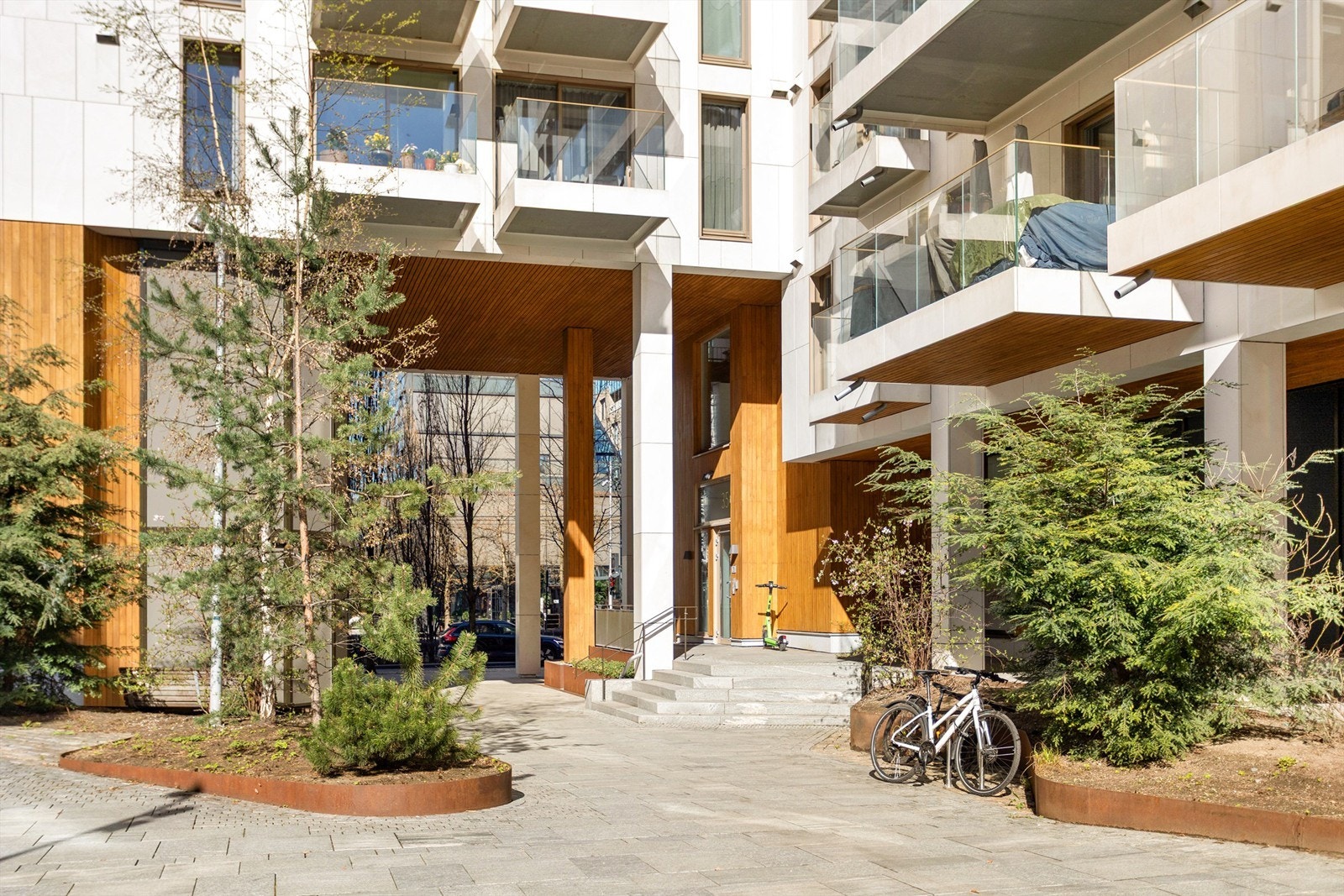 Pent opparbeidede fellesarealer med sykkelparkering og en innbydende inngang. Galleribilde