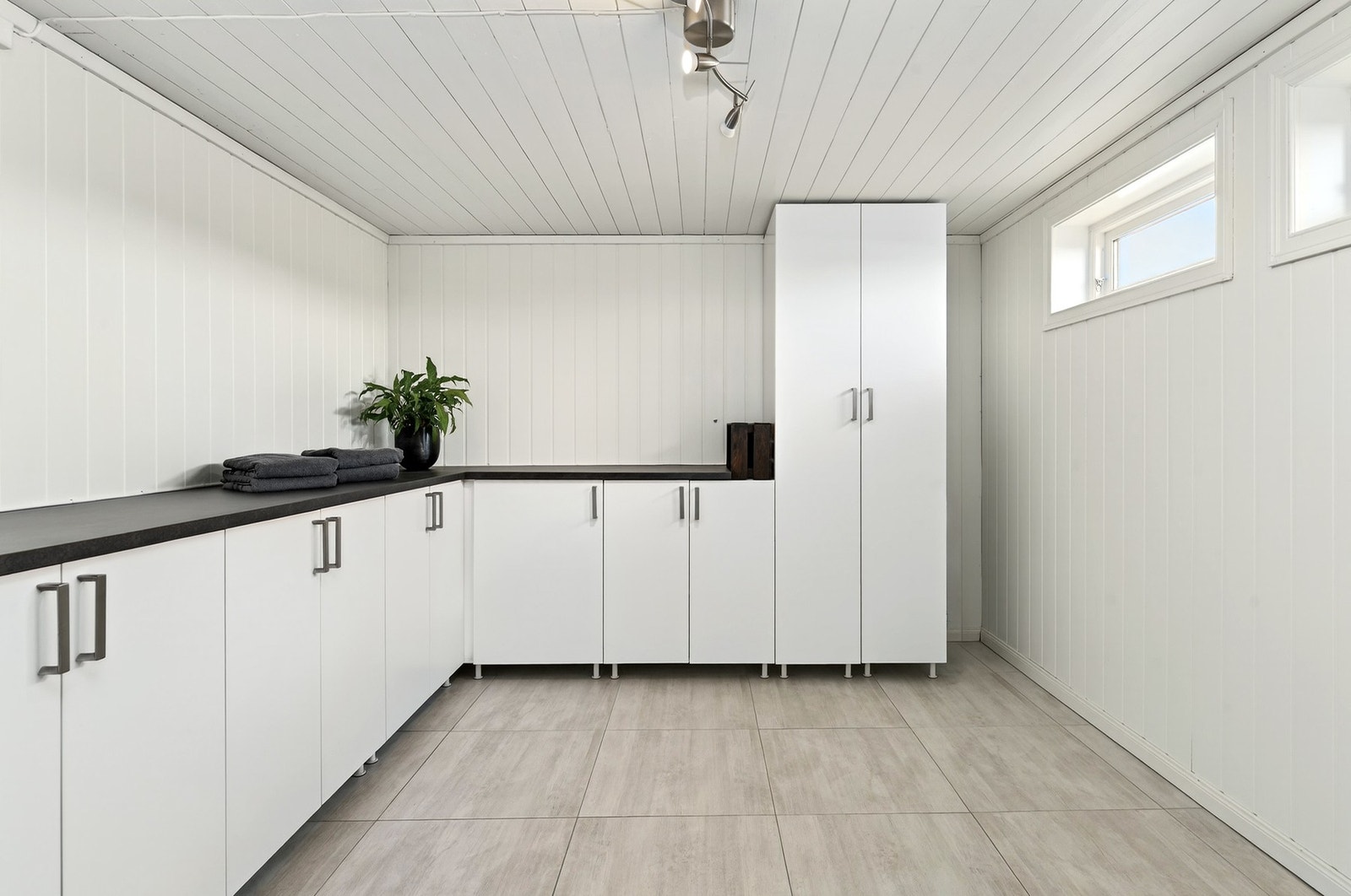 Romslig tørkerom med flis på gulv m/varmekabler, malte vegger og god benk- og skapplass. Galleribilde