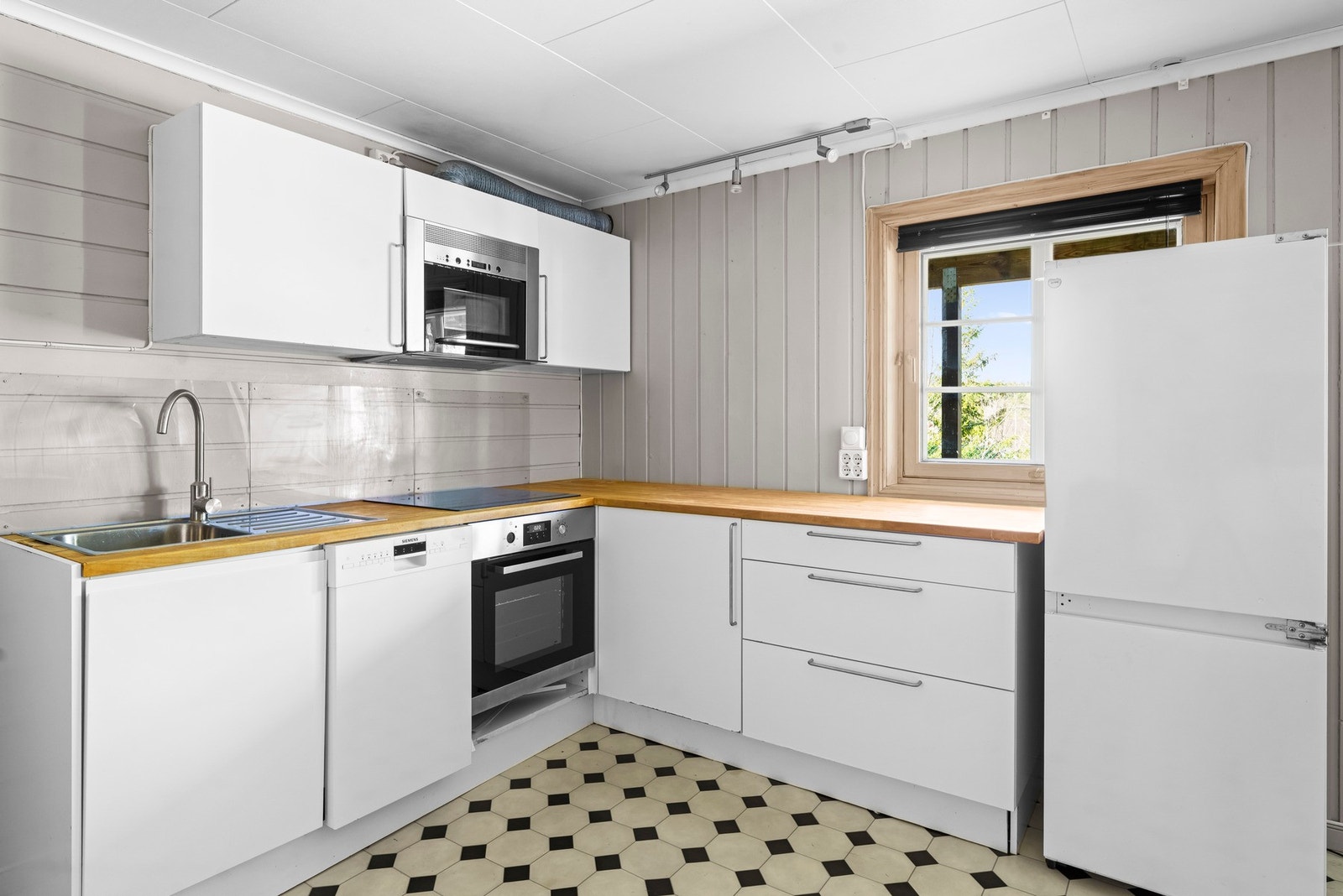 Kjøkkenet har innredning med glatte fronter. Benkeplaten er av heltre. Det er oppvaskmaskin (40 cm), komfyr, induksjonstopp, vannstoppsystem og micro. Avsatt plass til kjøl/fryseskap. Galleribilde