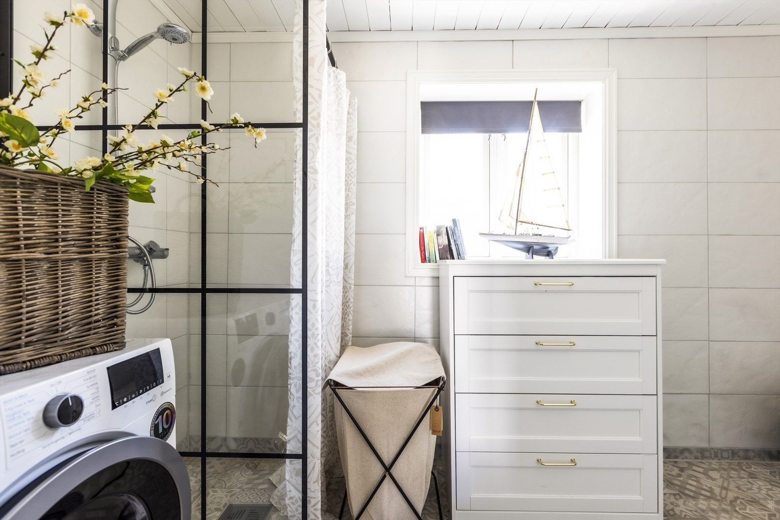Badet har en dusjløsning med glassvegg og forheng, samt vaskemaskin og servant i rustikk stil. Galleribilde