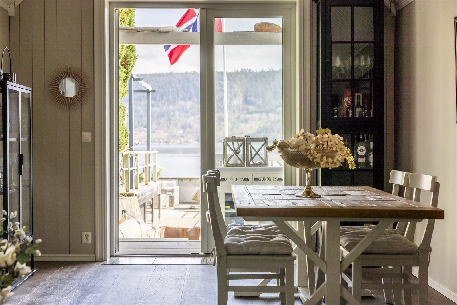 Spisestuen i annekset har store vindusflater som rammer inn utsikten mot vannet - et idyllisk sted å samle familie og venner Galleribilde