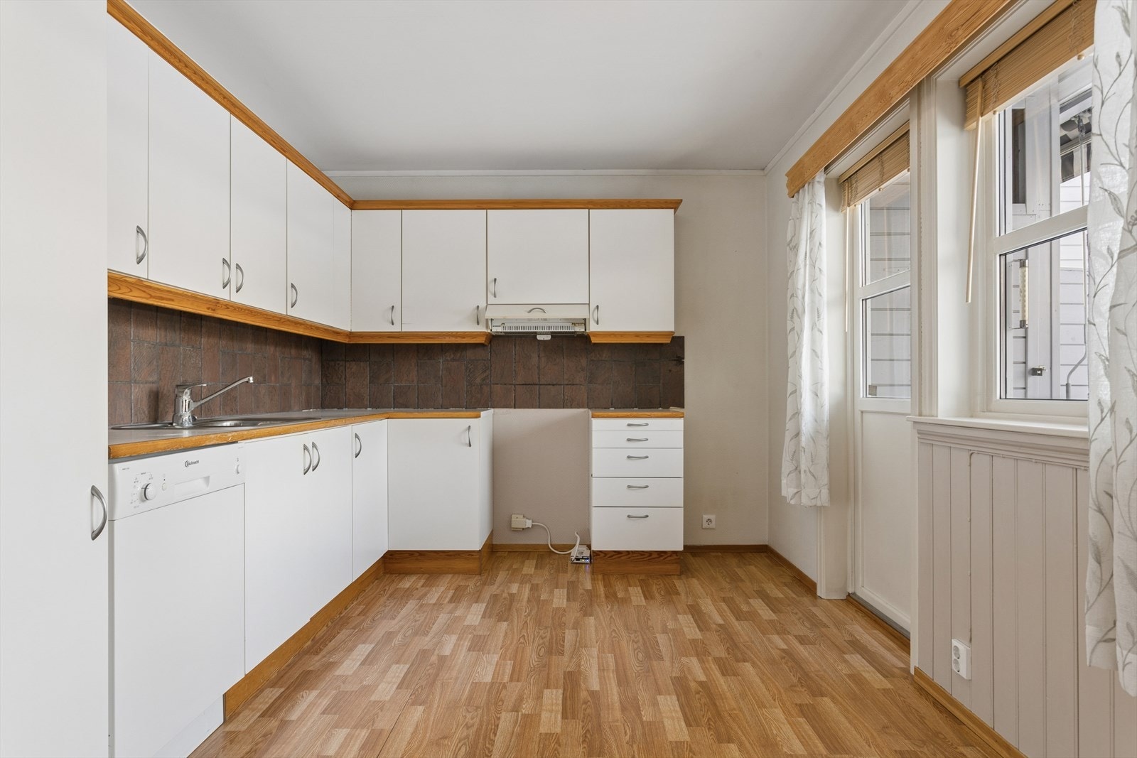 Kjøkkenet er lyst og har slette fronter samt benkeplate av typen laminat. Galleribilde