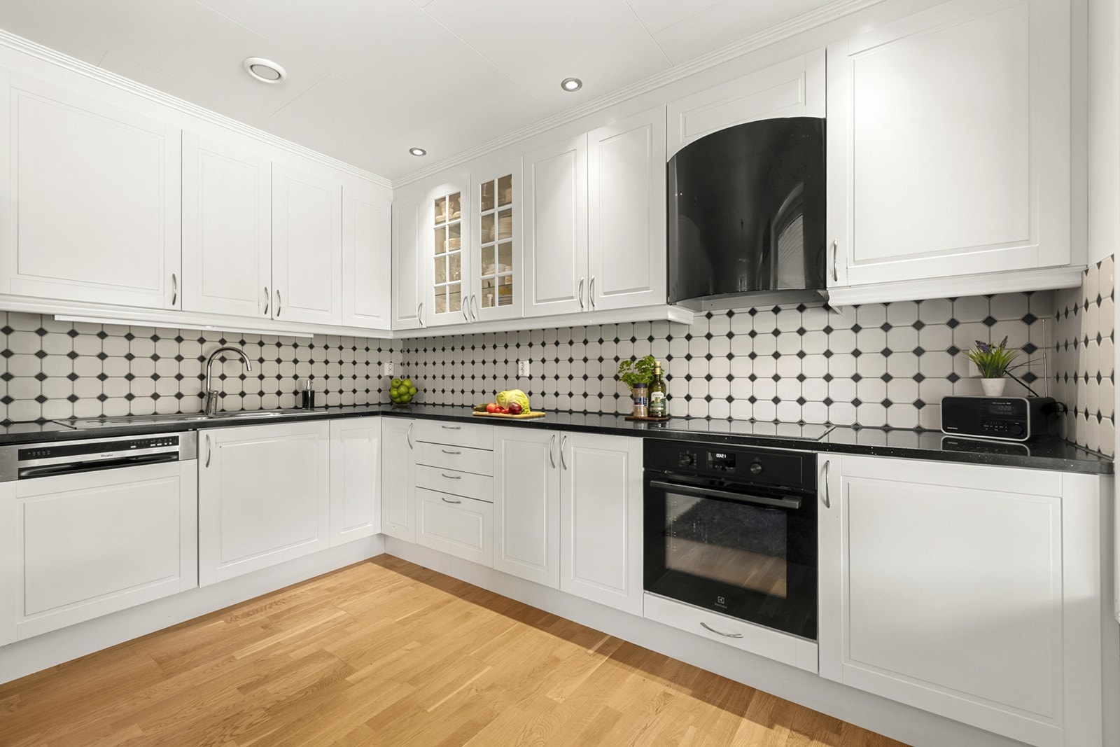 Kjøkkenet er utstyrt med integrerte hvitevarer, hvite profilerte fronter og en stor benkeplate. Galleribilde